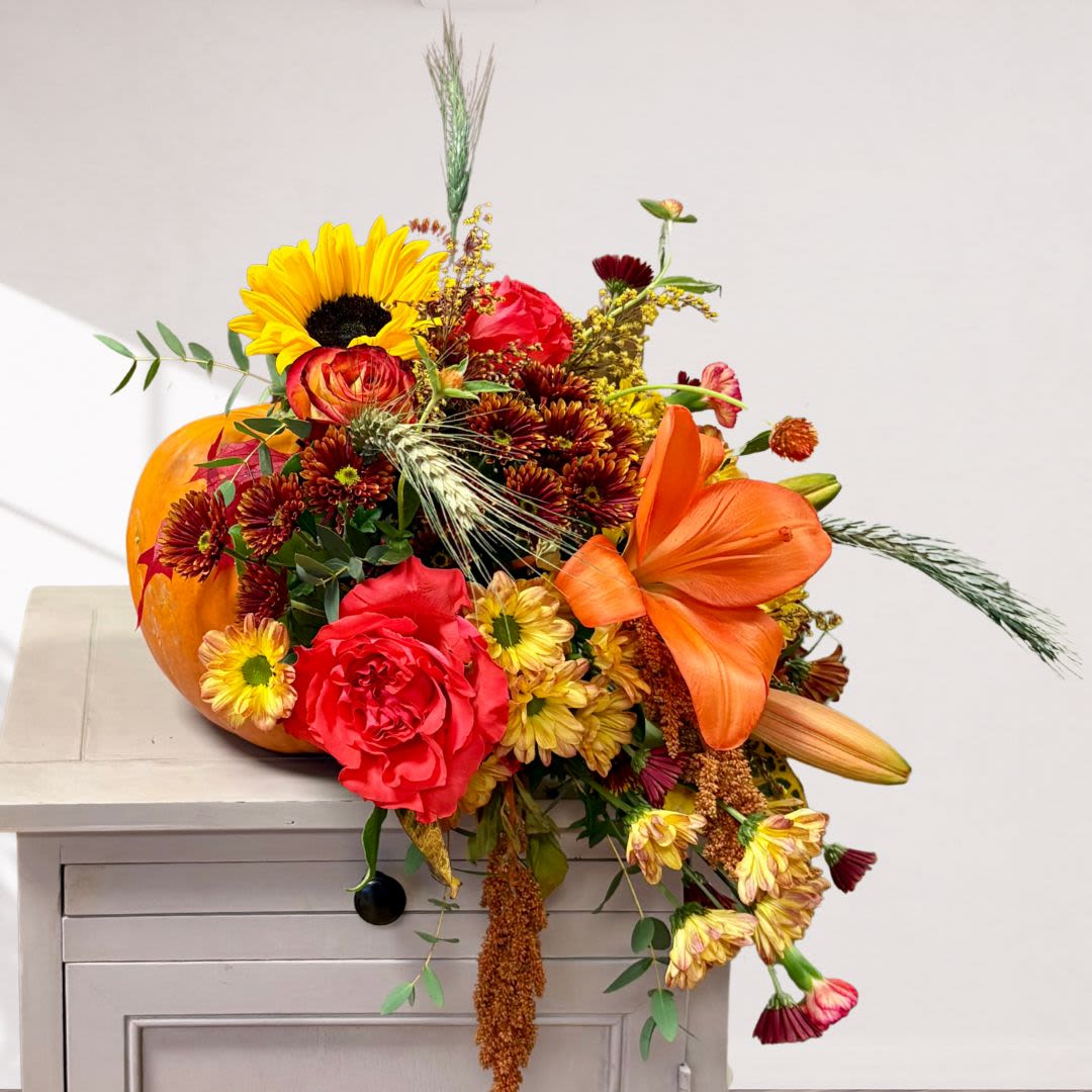 Autumn Pumpkin Cascade - This cascading natural pumpkin is perfect fr your front doorstep or entry table. Fall flowers include sunflowers, nmaranthus, roses, chrysanthemums, carnations and more in a natural pumpkin