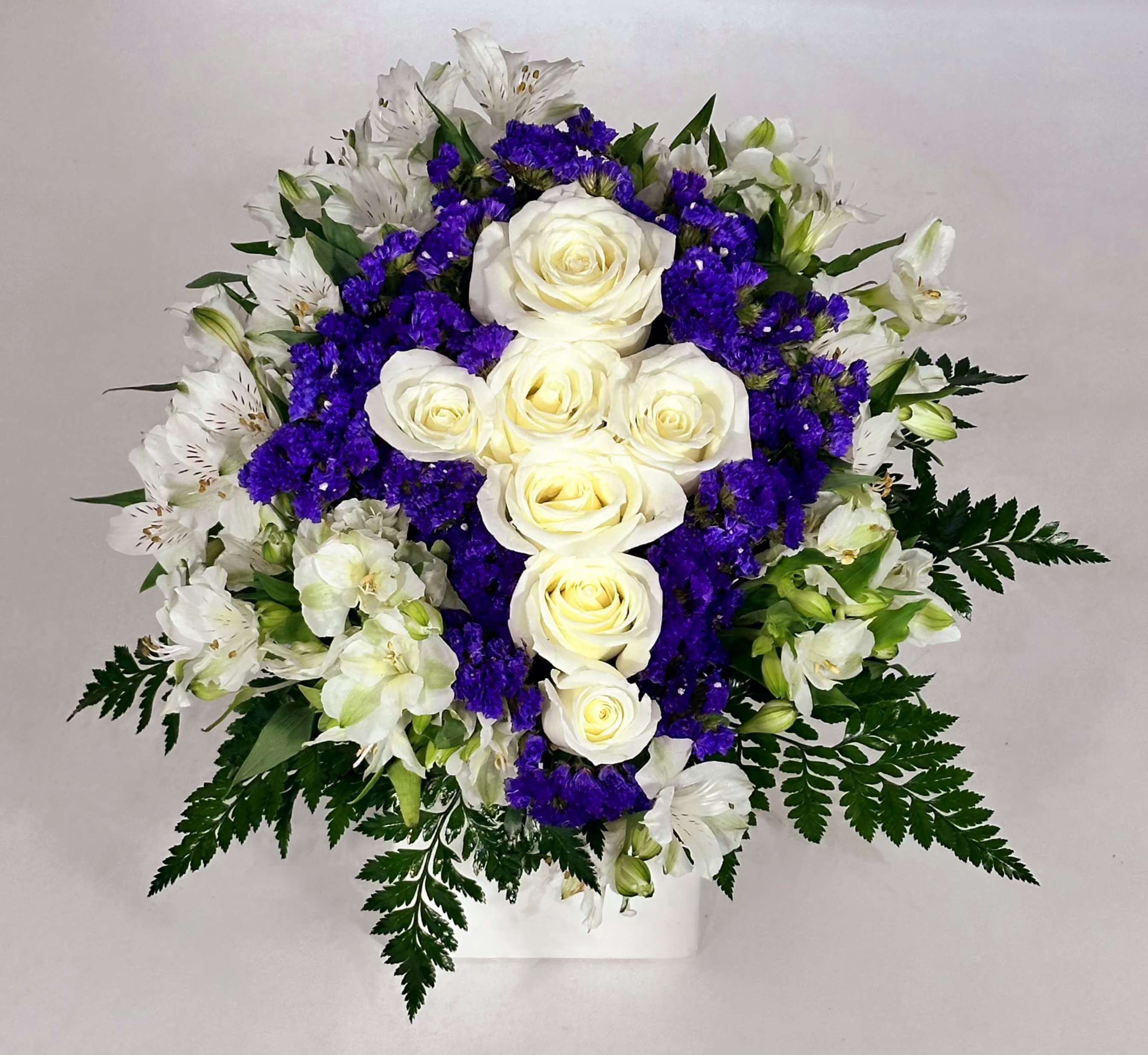 White Rose Cross  - Gorgeous, premium white roses is designed as a cross in a white cube with white alstromeria and purple statice. This stunning arrangement would be a wonderful gift for any occasion.  10' T 8' W