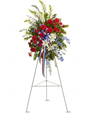 Sacred Duty Spray/Easel - Standing tall, proud and patriotic, this dazzling free-standing spray is like a fireworks display made of graceful flowers. Uniquely beautiful, it's a lovely way to honor a great loss. A gorgeous selection of flowers such as white lilies and snapdragons, blue delphinium, red carnations and miniature carnations, eucalyptus and more create this all-American spray.