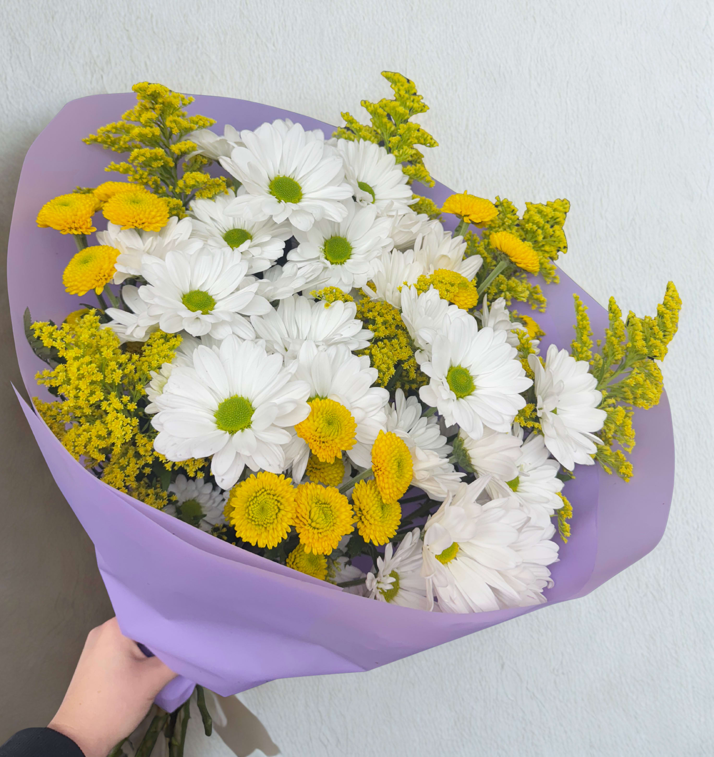 Sunshine daisy Sunshine daisy - A bright and playful bouquet featuring white daisies, yellow button chrysanthemums, and solidago, wrapped in elegant lavender paper . Perfect for any occasion that calls for positivity and warmth. Note: Flower varieties may be substituted with equal value seasonal blooms for freshness and quality.