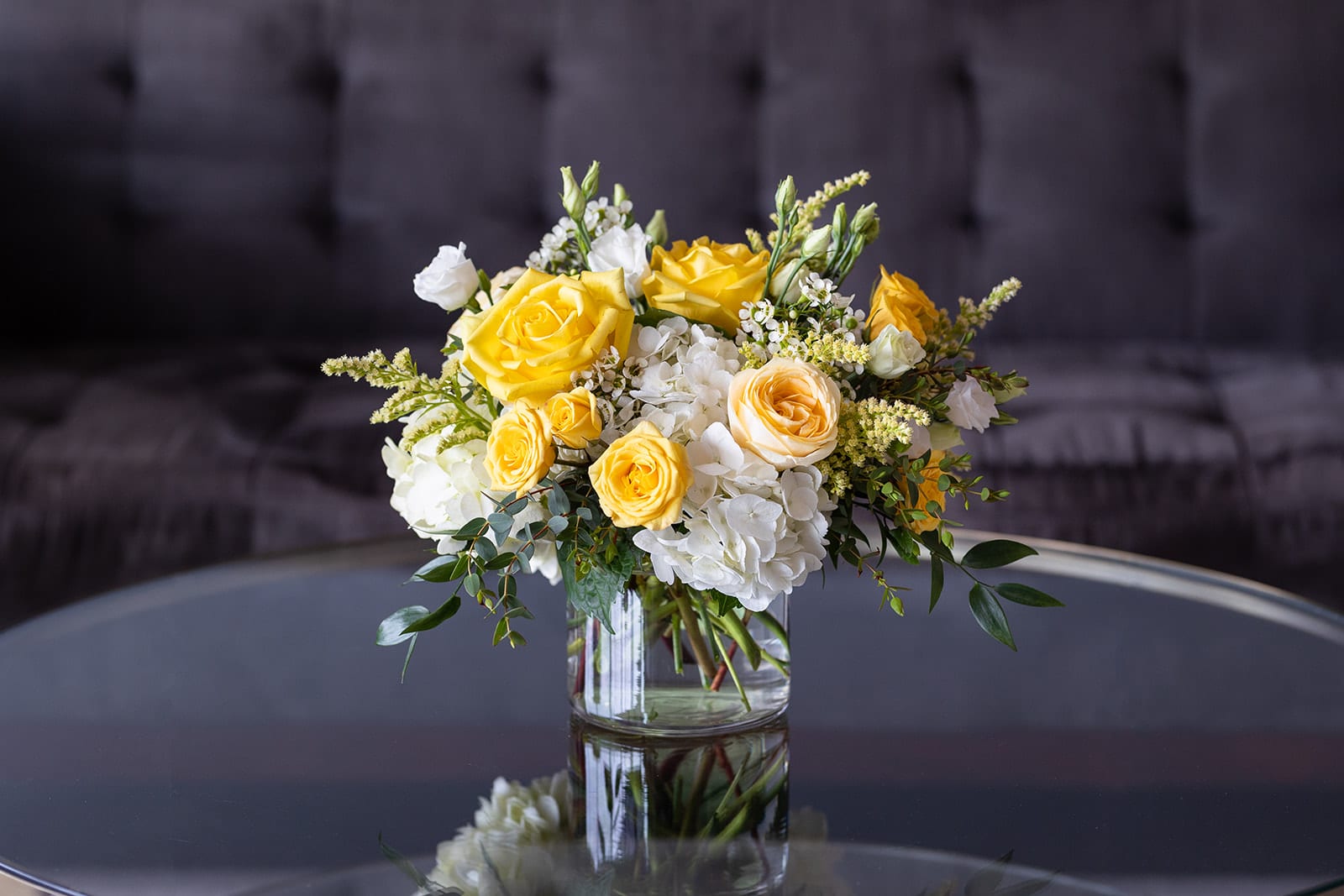 Limoncello Collection - Market Size  - Inspired by the sunny days on the Amalfi Coast, our Limoncello Collection is bright, zesty and full of yellow and cream colored blooms. A crisp white vase filled with garden roses, roses, spray roses, hydrangea, snapdragons and Lisianthus - all accented with Italian Ruscus and Solidago. Our market collection features fresh cut flowers in a clear glass vase. We created this size to send for birthdays, a pick-me-up, a thank you or to also work as a centerpiece for parties and events. Market size designs are made in a 5” clear glass cylinder vase.   Dimensions: The market size arrangements are approximately 10” tall and 8” wide.   