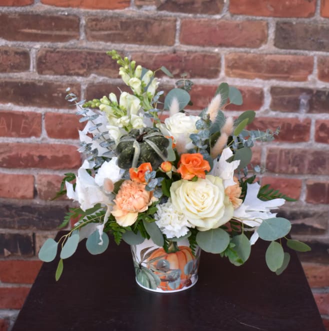 The First Frost The First Frost - Crisp air, icy patterns on the windows, and gathering ripe harvests from the garden...the first frost is upon us and this bouquet brimming with white roses, orange spray roses, white snapdragons, orange carnations, accents of bleached leaves and eucalyptus; designed in a white pumpkin container, is the perfect way to celebrate the season!