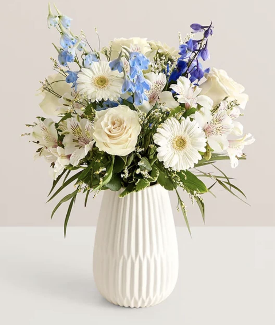 Winter Blossoms Bouquet - Send the calming beauty of winter in a bouquet. Hand designed by our florists, this elegant gathering features seasonal blue and white blooms, along with accents of cascading greenery. It’s arranged in our keepsake White Modern Vase to help celebrate the season in style.