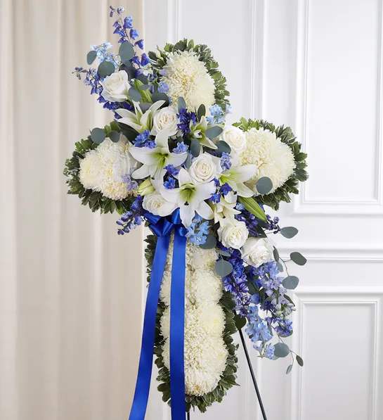 Peace &amp; Prayers - Blue &amp; White or Pastel Standing Cross - If faith was an important part of their life, our standing cross arrangement is a special way to honor a loved one’s memory. Our expert florists handcraft each of these impressive displays with a bed of white mums in the shape of a cross, and accent with a cascade to match and spiral eucalyptus. This floral tribute is a beautiful way for family to offer peace and comfort during a difficult time.