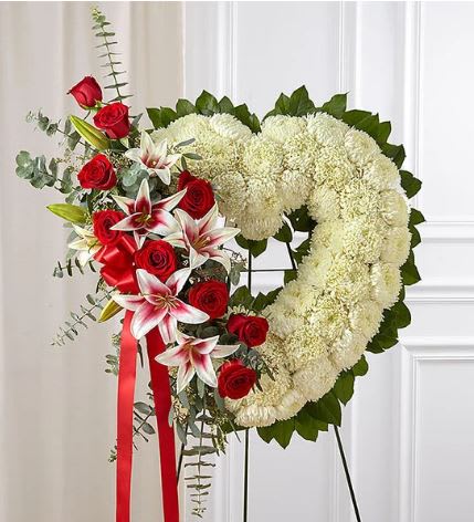 Always Remember Floral Heart Tribute - Red Rose &amp; Lily - The passing of someone we love deeply requires a special tribute. Our open heart standing arrangement of fresh white blooms, accented by red roses and Stargazer lilies cascading down one side and adorned with a red satin ribbon, will help you express the devotion and sympathy in your heart.