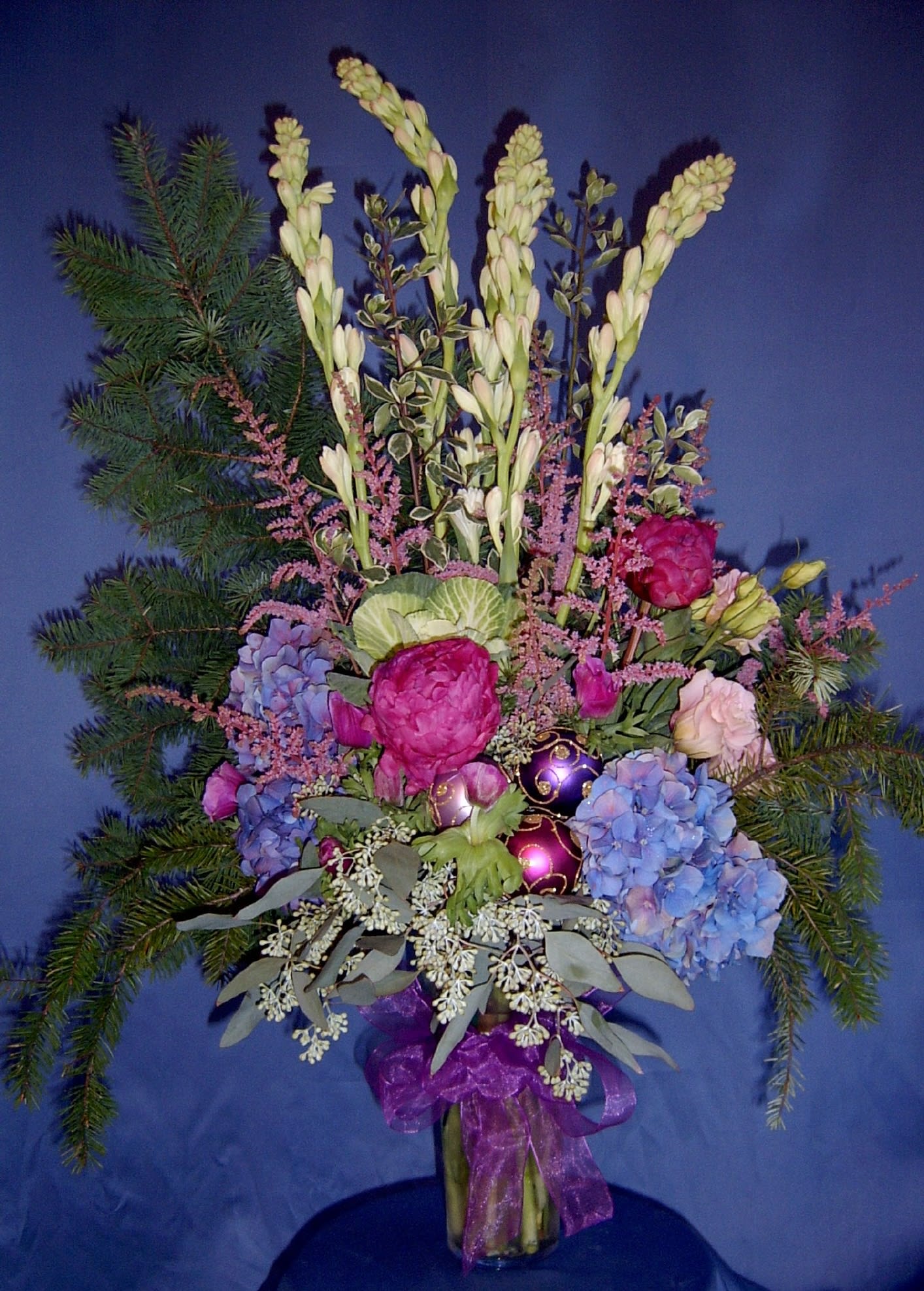 Jewel tone Winter Celebration with Peonies Jewel tone Winter Celebration with Peonies - Our most colorful perky display of formal holiday event flowers. Use this to decorate your foyer for the holidays or to dress up a corporate party. The fragrance of winter pine and sweet tuberose flower and the glamour of these premium winter flowers makes a stunning impression surely everyone will agree. Order ahead to get the best selection for your event. Here, we used hydrangea, peonies, tuberose, kale, anemone, lisianthus, astilbe, eucalyptus and pine.* We will accent your design with Christmas ornaments if you like - designer's choice of style. Merry Christmas and Happy Holidays!