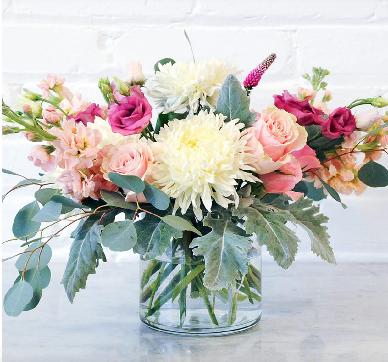Whispering Willow Whispering Willow - Whispering Willow is one of our most loved arrangements, this design features fragrant pink roses, warmly scented stock, and soft white standard mums, all gathered in a clear glass vase.