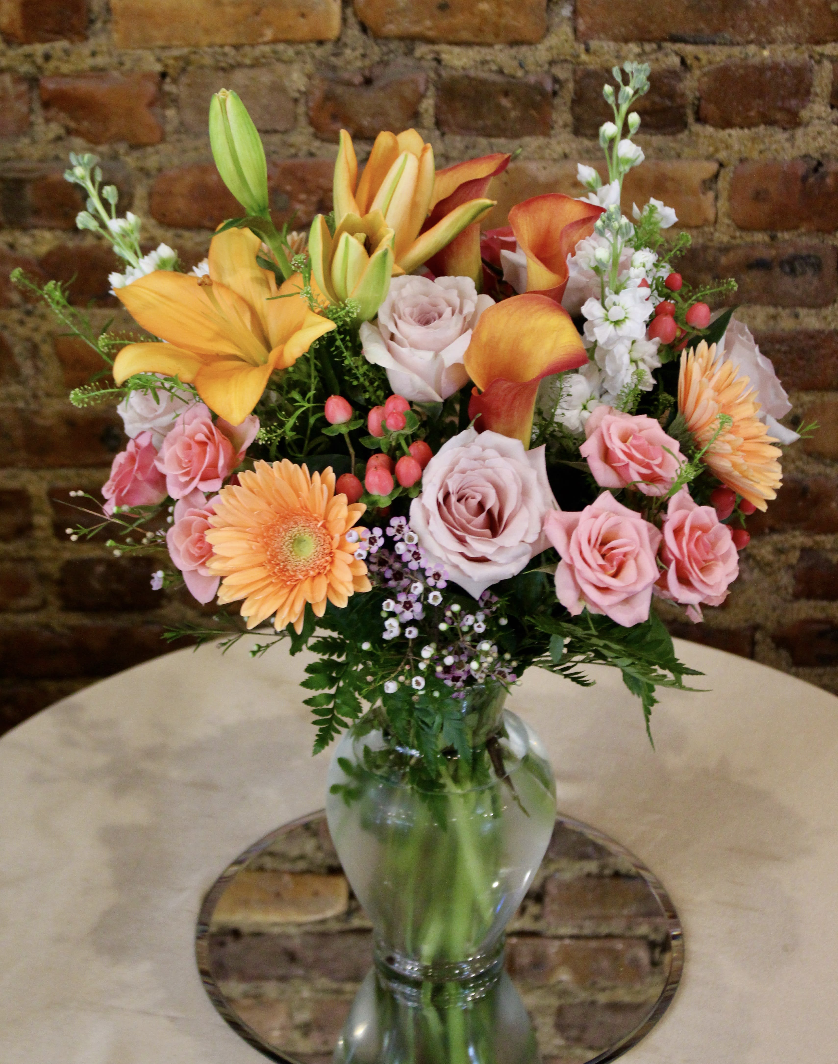 The Essence Bouquet  - The Essence Bouquet is a bright and sunny way to celebrate any of life's special moments! Bringing energy and beauty straight to your special recipient's door, this fresh flower arrangement unites orange and peach toned floral's designed in a decadent glass vase  Orientation: All-Around All prices in USD ($) Standard (Shown), Deluxe , Premium