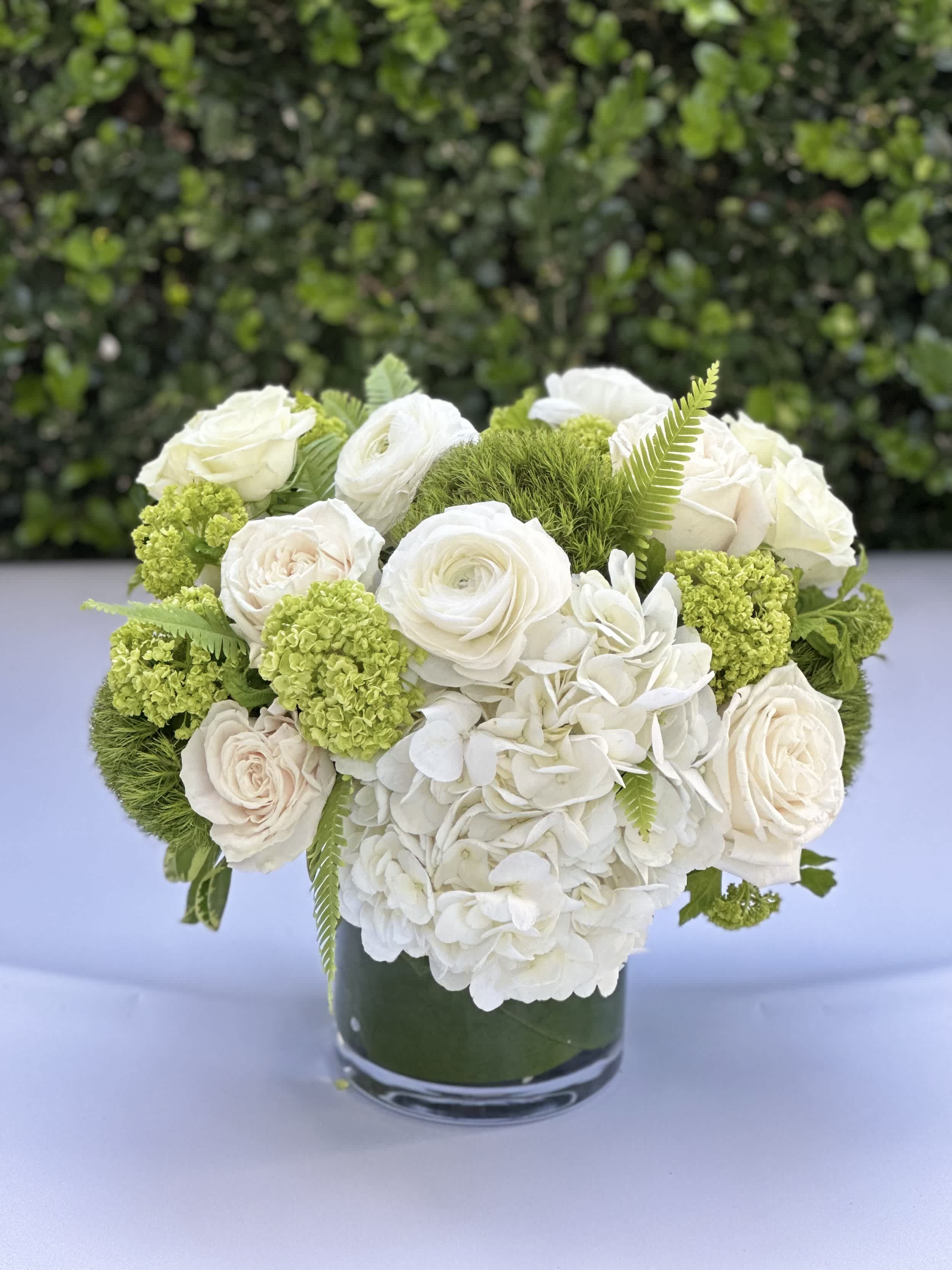 The Marilyn - A pristine collection of crisp white roses, ranunculus, and hydrangea is accented with green trick, and viburnum.