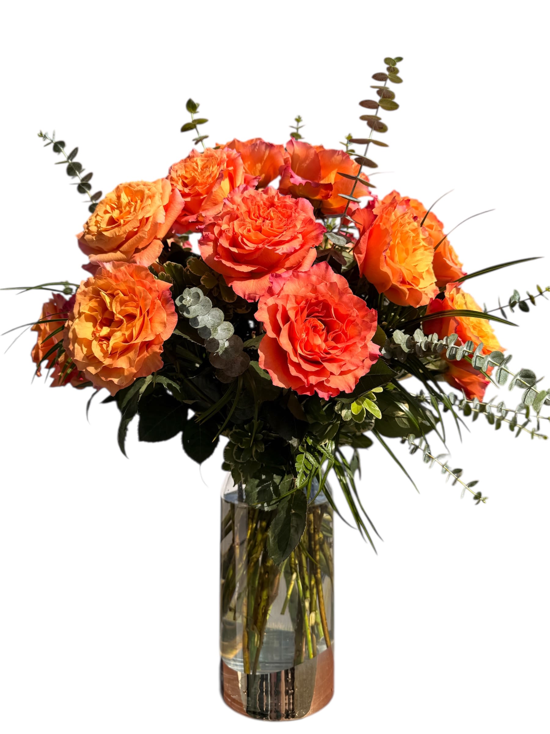 Sunset Roses Sunset Roses - An exquisite bouquet featuring 24 vibrant, coral/apricot roses that evoke the warm, rich colors of a setting sun. Accented with silvery eucalyptus and lush greenery, this arrangement offers a passionate and comforting display.