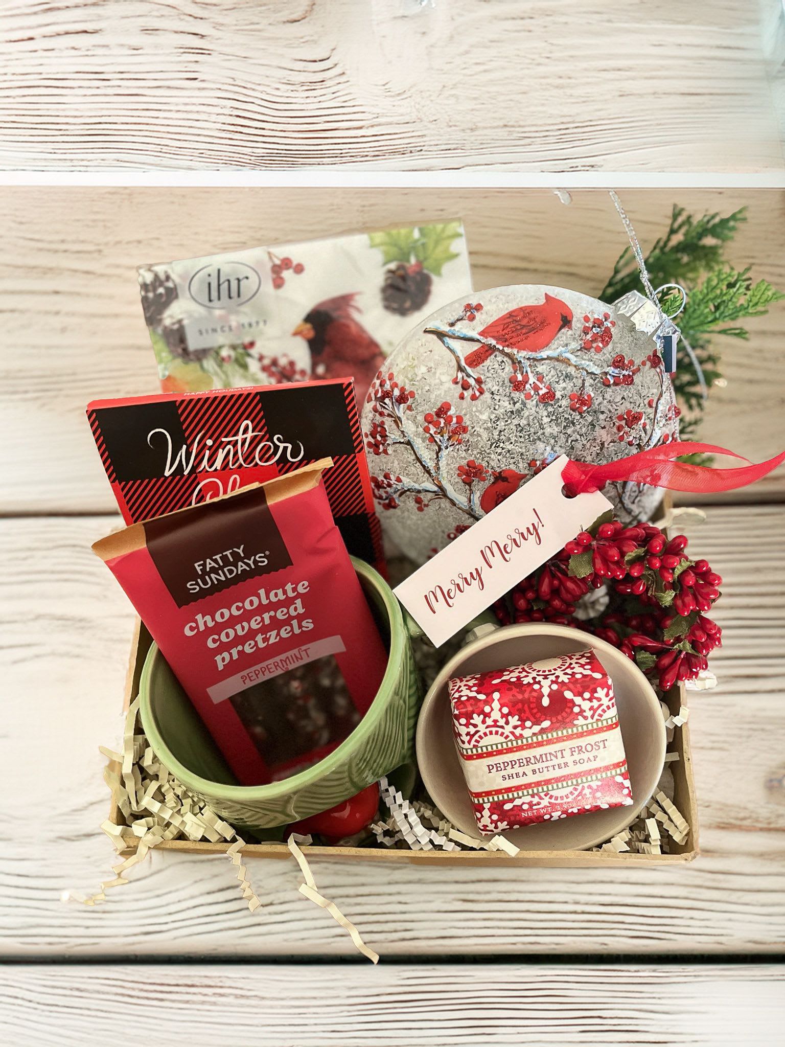 Cardinal Kiss Winter Gift Box  - Cardinals are a treasured sight in the winter season and also serve as a reminder of loved ones who have passed on. Send a token of cheer with this gift box that includes a charming package of cardinal themed paper cocktail napkins, a glass cardinal ornament, mini beaded wreath ornament, winter chai tea, peppermint chocolate covered pretzels, seasonal mini soap, beautiful cardinal motif mug and themed mini trinket dish.   Packaged in our signature Kraft gift box. 