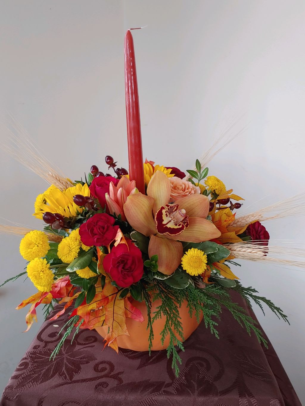 Candlelight Pumpkin - A ceramic candlelight pumpkin for your thanksgiving centerpiece. An assortment of Roses, cymbidium orchid, hypercium berries, leaves, and other seasonal flowers.