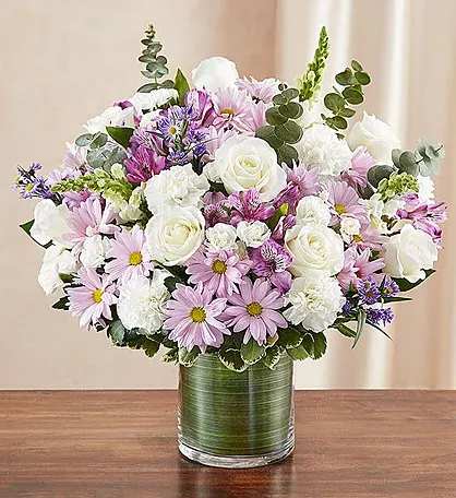 deluxe cylinder bouquet - Arrangement of white roses, snapdragon and carnations, lavender daisy poms and monte casino and purple alstroemeria; accented with fresh greenery Hand-designed by our expert florists in a stylish clear glass cylinder vase lined with a Ti leaf ribbon; vase measures 6&quot;H Large arrangement measures approximately 16&quot;H x 17&quot;L Medium arrangement measures approximately 15&quot;H x 16&quot;L Small arrangement measures approximately 14&quot;H X 15&quot;L A lovely gift for the service or for the home of family members or friends Our florists hand-design each arrangement, so colors, varieties and vase may vary due to local availability Alstroemeria may arrive in bud form and will open to full beauty over the next 2-3 days Recommended For You
