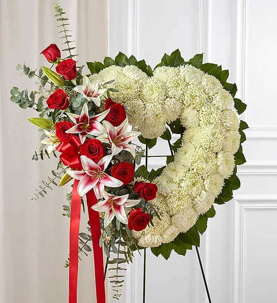white and pink and red heart tribute - Our florists hand-design each arrangement, so colors and varieties may vary due to local availability Arrangement of roses, Stargazer lilies, mums, spiral and seeded eucalyptus and salal Arrangement measures approximately 28&quot;H x 26&quot;L without easel Appropriate to send to the funeral service