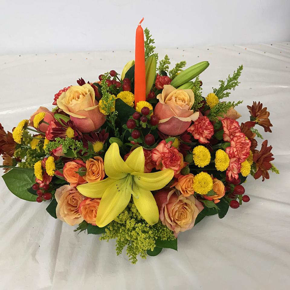 Thanksgiving Spirit - Fall colors assorted fresh flowers arranged in a short container with a candle, it's the perfect holiday centerpiece.
