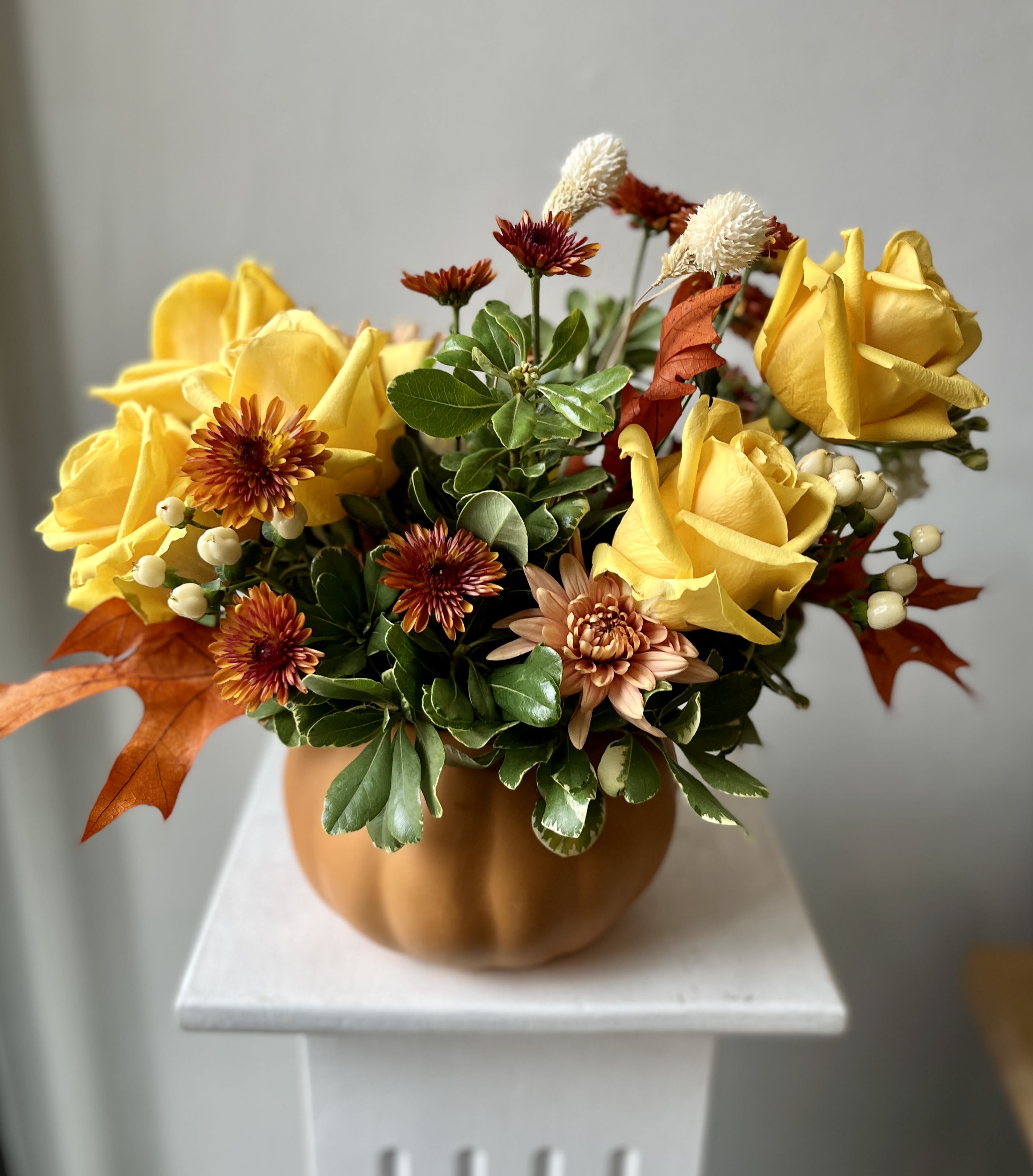 Hello Pumpkin - Mellow Yellow Roses with accents mum and heavy greens for his artistic arrangement in an orange pumpkin 