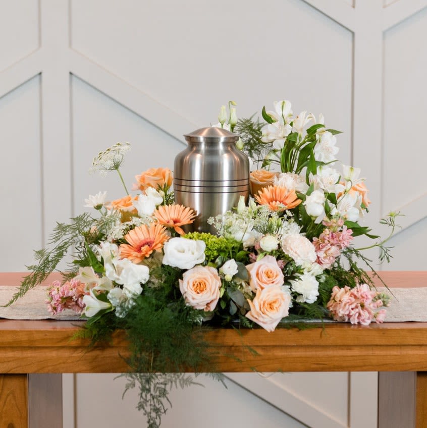 Alliance - A mix of peach gerbera daisies, peach roses, and white lisianthus are used to create a wildflower frame around an urn.   Approximate Dimensions: 24&quot; H x 17&quot; W