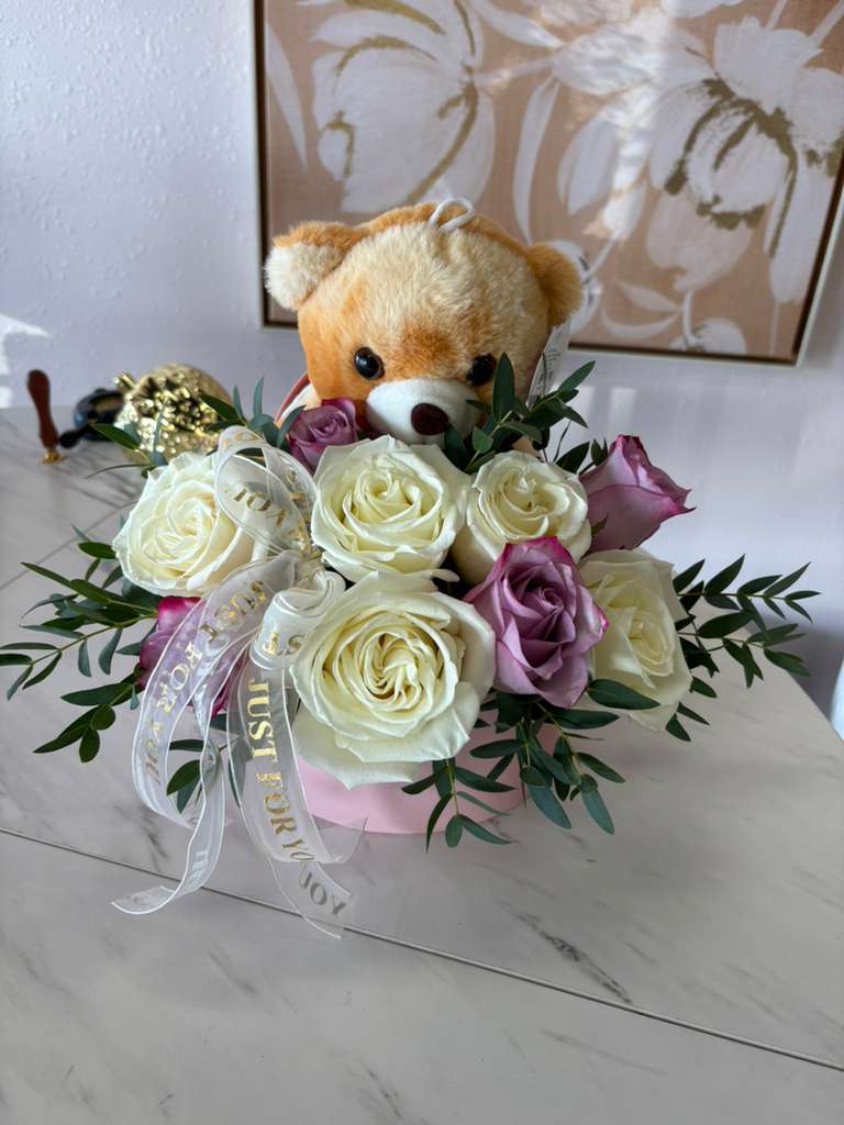 Welcome basket for baby girl | Floral arrangement with a stuffed animal and roses - A tender and elegant gift to celebrate the arrival of a beautiful baby girl. This charming welcome basket combines the warmth of a soft teddy bear with the freshness of natural flowers in shades of cream, pink, and lilac. Each flower has been carefully selected to convey love, purity, and sweetness, while the pink bowed basket adds a delicate and feminine touch that will captivate at first sight. Perfect for baby showers, hospital visits, or congratulations on the birth, this arrangement is a loving gesture that will bring a smile to the new parents' faces.