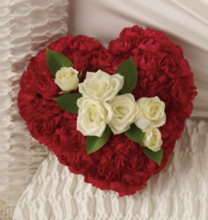 Heart Sympathy Casket Pillow  Heart Sympathy Casket Pillow  - This elegant casket pillow is lovingly crafted in the shape of a delicate heart, symbolizing love and remembrance. It is filled with a soft, fragrant arrangement of fresh flowers, offering a gentle and comforting presence inside the casket. The pillow features graceful ribbon scripting across its surface, beautifully embroidered with heartfelt words or initials to honor the loved one. Its tender design and floral embellishments serve as a heartfelt tribute, providing a touch of warmth and serenity during a time of remembrance.  The Heart measures 12" top to bottom.