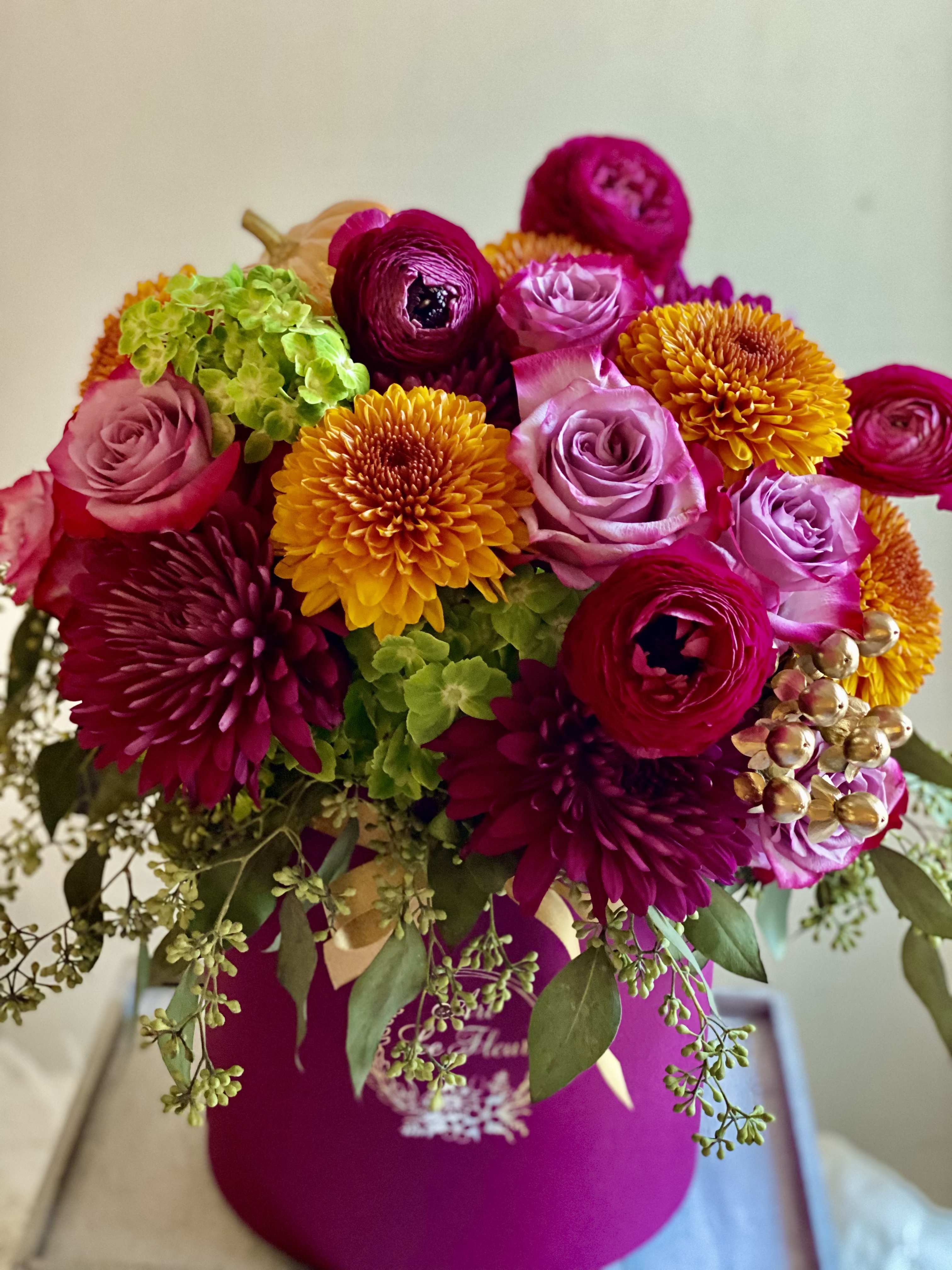 Autum Glory Autum Glory - Nested in a wine color hatbox is this bountiful composition of blooms in reach golden, burgundy, orange, green and purple tones captures the warmth and sophistication of the season-A perfect harmony of texture and color that feels both natural and refined. Perfect for gifting or adding a touch of seasonal flowers to any space.