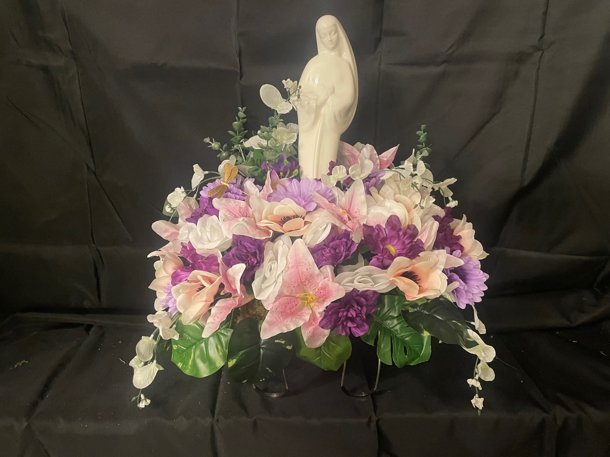Gravestone Saddle - This arrangement is made to sit atop your loved one's gravestone. Handmade inhouse of artificial flowers. It's on an adjustable base to make for an easy fit. This Item is for pick-up only. If you'd like it delivered to a cemetery, please call 814.536.0536