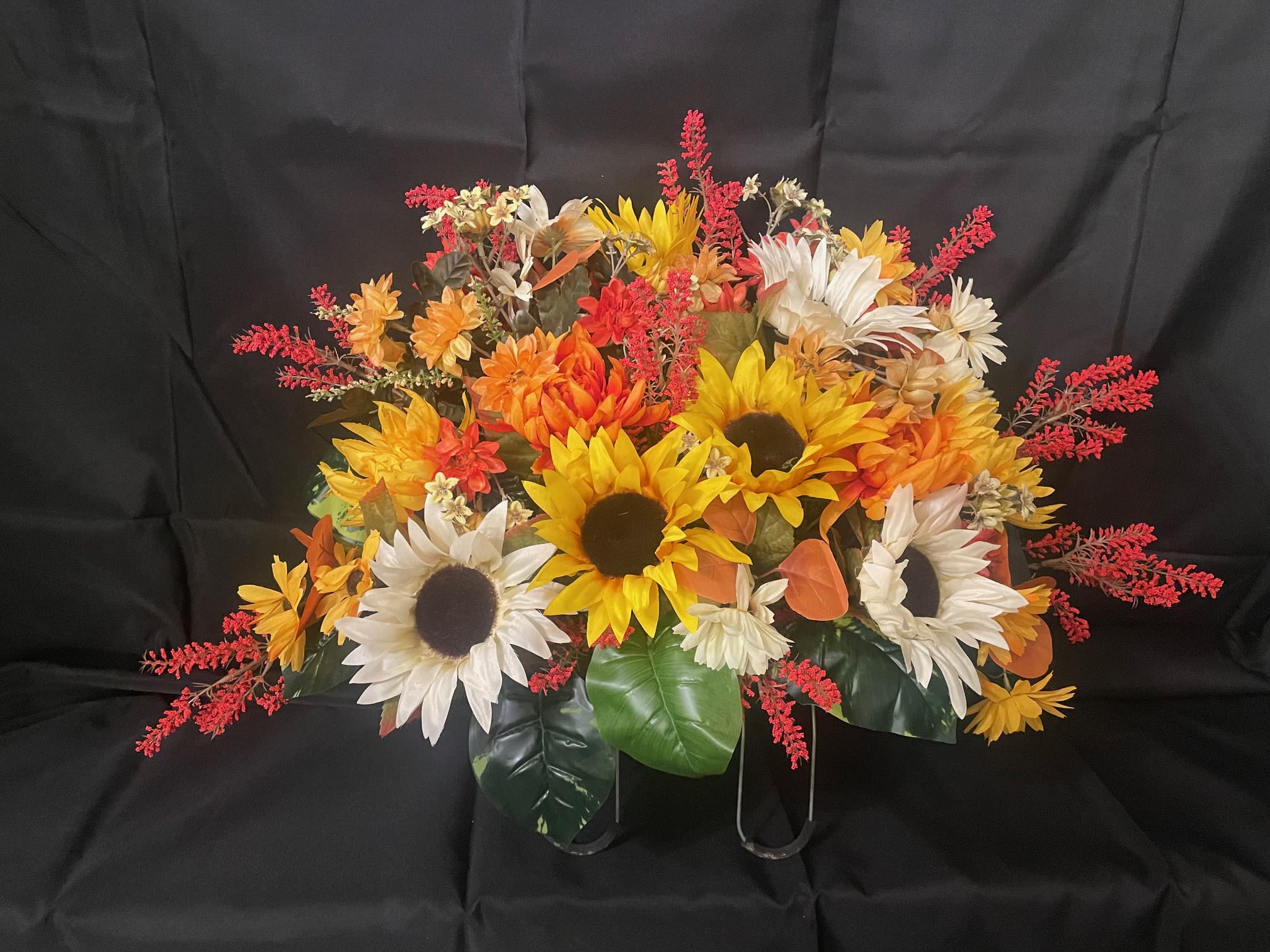 Gravestone Saddle Fall - This arrangement is made to sit atop your loved one's gravestone. Handmade inhouse of artificial flowers. It's on an adjustable base to make for an easy fit. This Item is for pick-up only. If you'd like it delivered to a cemetery, please call 814.536.0536