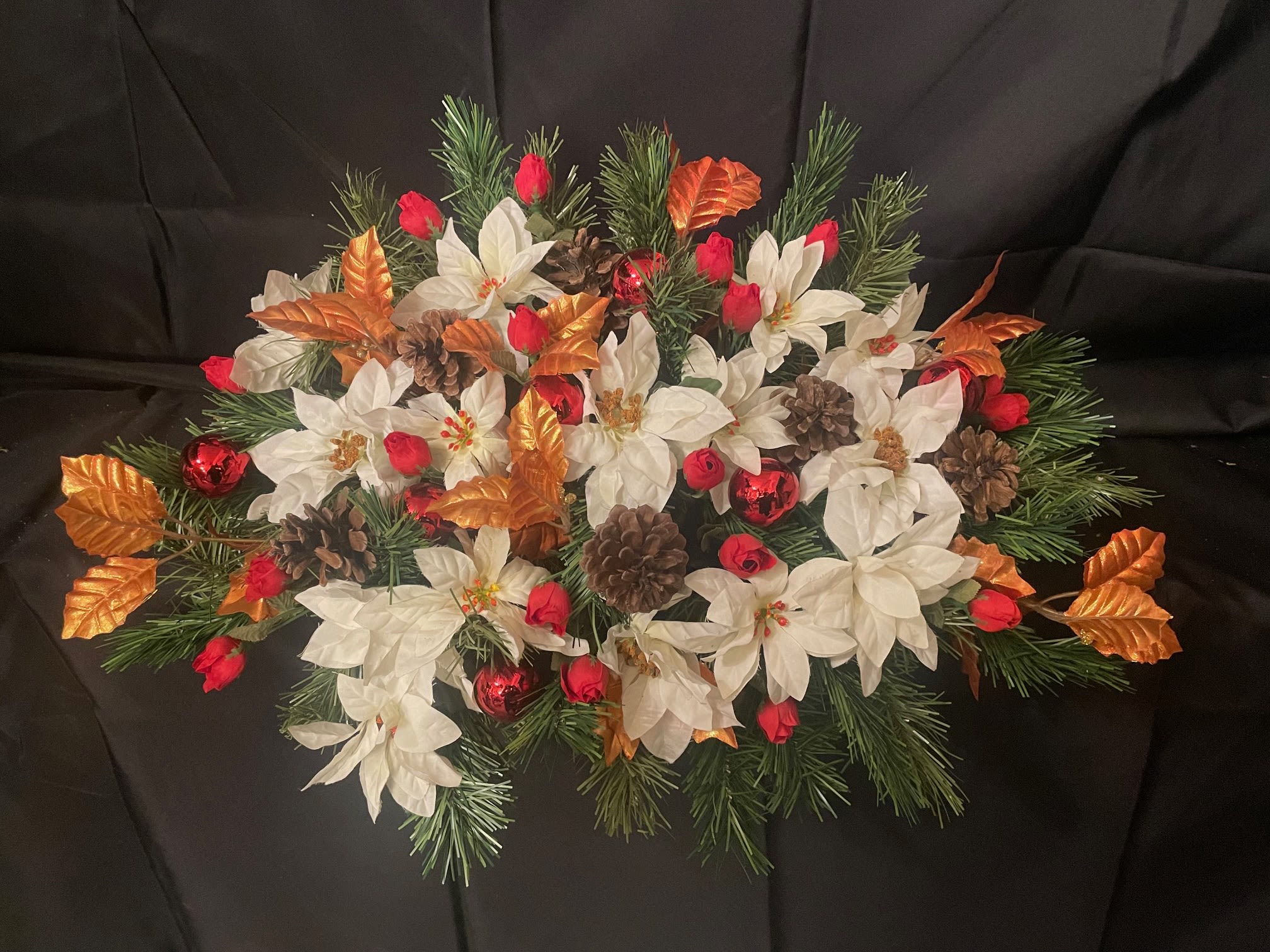 Gravestone Saddle, Christmas - This arrangement is made to sit atop your loved one's gravestone. Handmade inhouse of artificial flowers. It's on an adjustable base to make for an easy fit. This Item is for pick-up only. If you'd like it delivered to a cemetery, please call 814.536.0536