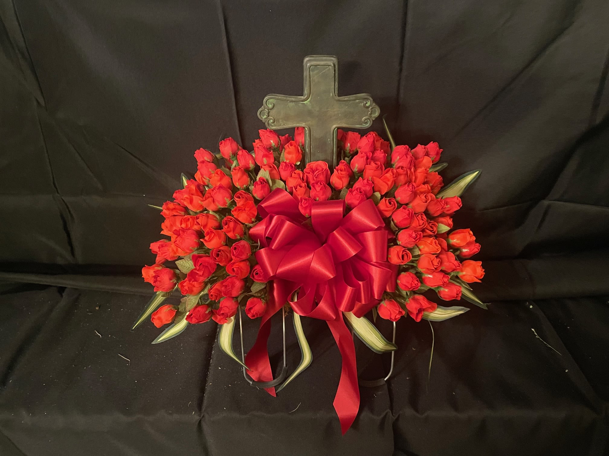 Gravestone Saddle, Cross - This arrangement is made to sit atop your loved one's gravestone. Handmade inhouse of artificial flowers. It's on an adjustable base to make for an easy fit. This Item is for pick-up only. If you'd like it delivered to a cemetery, please call 814.536.0536
