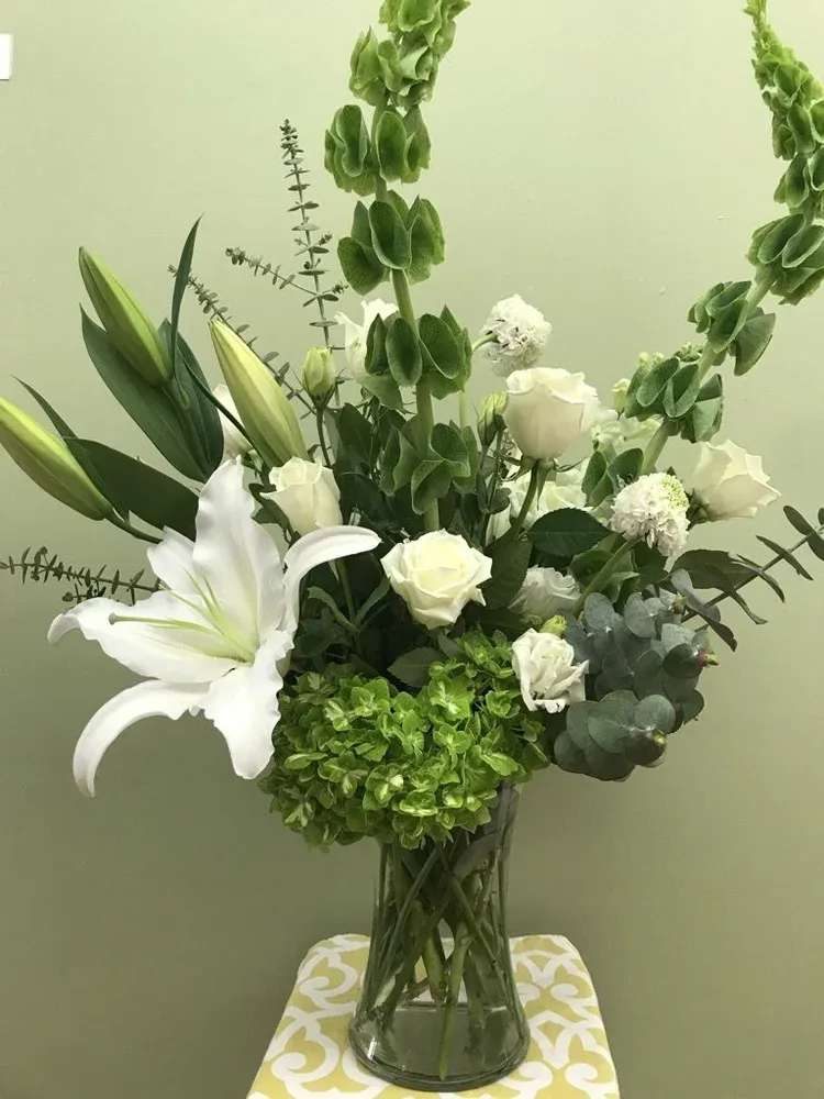 Get By With A Little Help From Our Friends - An arrangement of white and green flowers in a tall clear vase. A neutral arrangement suitable for a sympathy going to a church or a home.