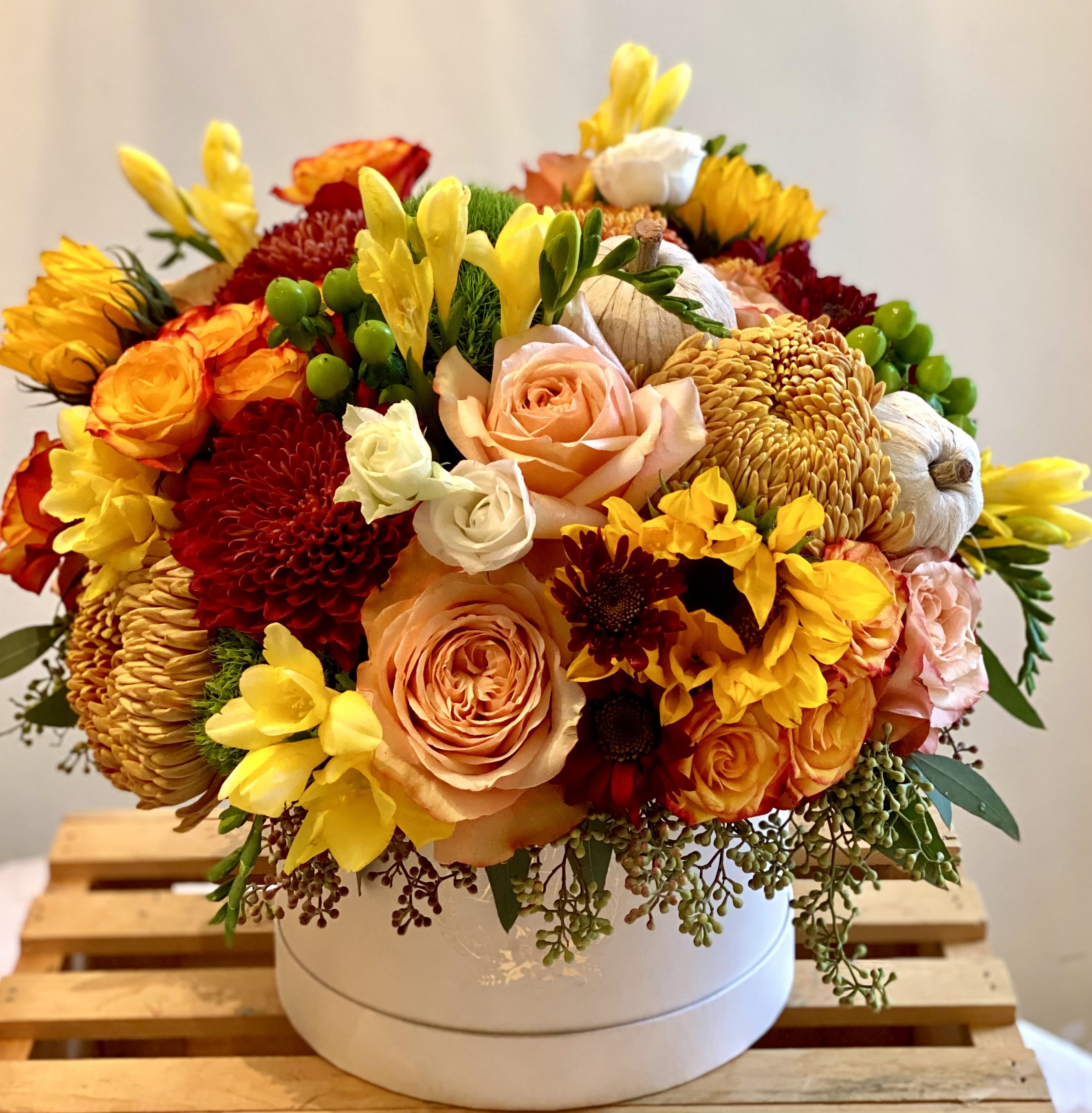 Golden Harvest Hatbox Golden Harvest Hatbox - A radiant celebration of the season, this charming hatbox overflows with golden roses, cheerful sunflowers, freesia, hypericum berries, delicate spray roses and more. Makes for an impressive and exceptional gift, validation or celebration or simply an aesthetic gathering of seasonal and warm flowers.