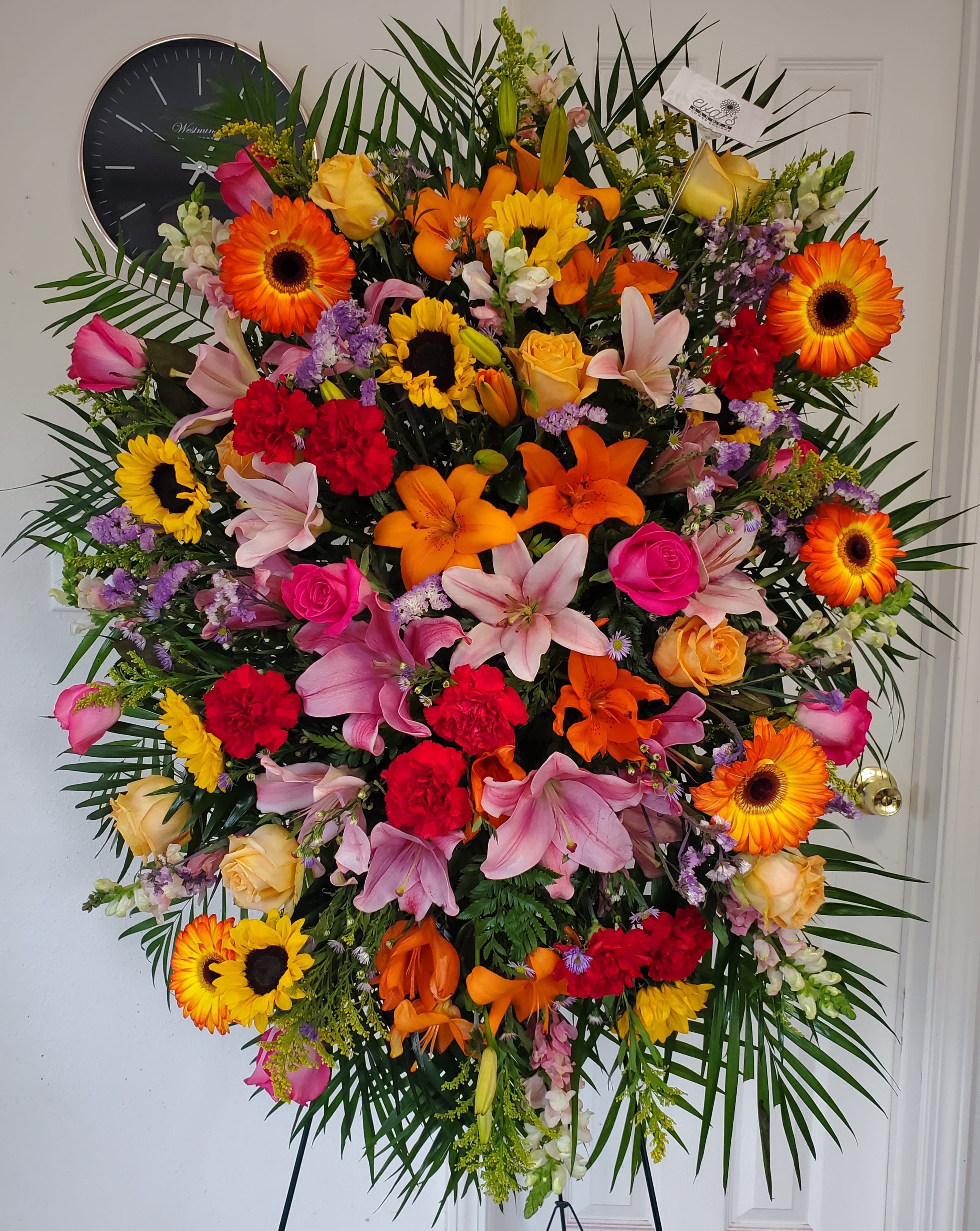 Multicolored Funeral Spray - Funeral spray filled with a colorful array of lilies, sunflowers, roses, carnations, snapdragons, solidaster, solidago, statice, gerber daisies, and monte casino.  (Picture depicts a premium product; standard &amp; deluxe size available upon request)