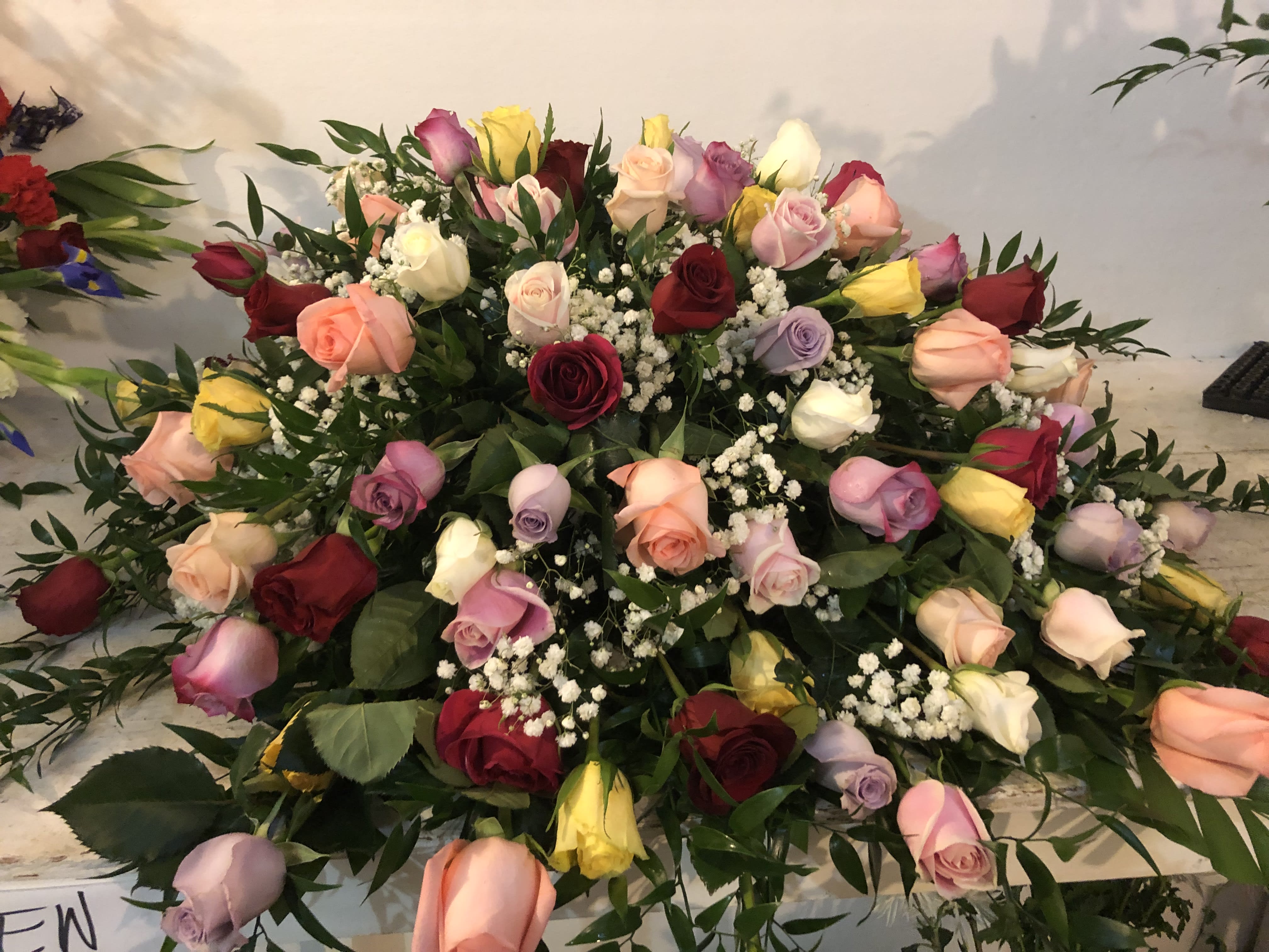 A Wonderful Life Casket Spray - Multicolored roses accented with soft baby's breath is the ultimate tribute to a life well lived. Each rose symbolizes one year of your loved one's life. As shown for 80 years of life celebrated.  We are happy to customize the years of life for your special person. Floral, plant, and hard good substitutions may be made as needed depending on availability. If you have any questions about your order, please call us and we will be happy to speak with you about your selection.