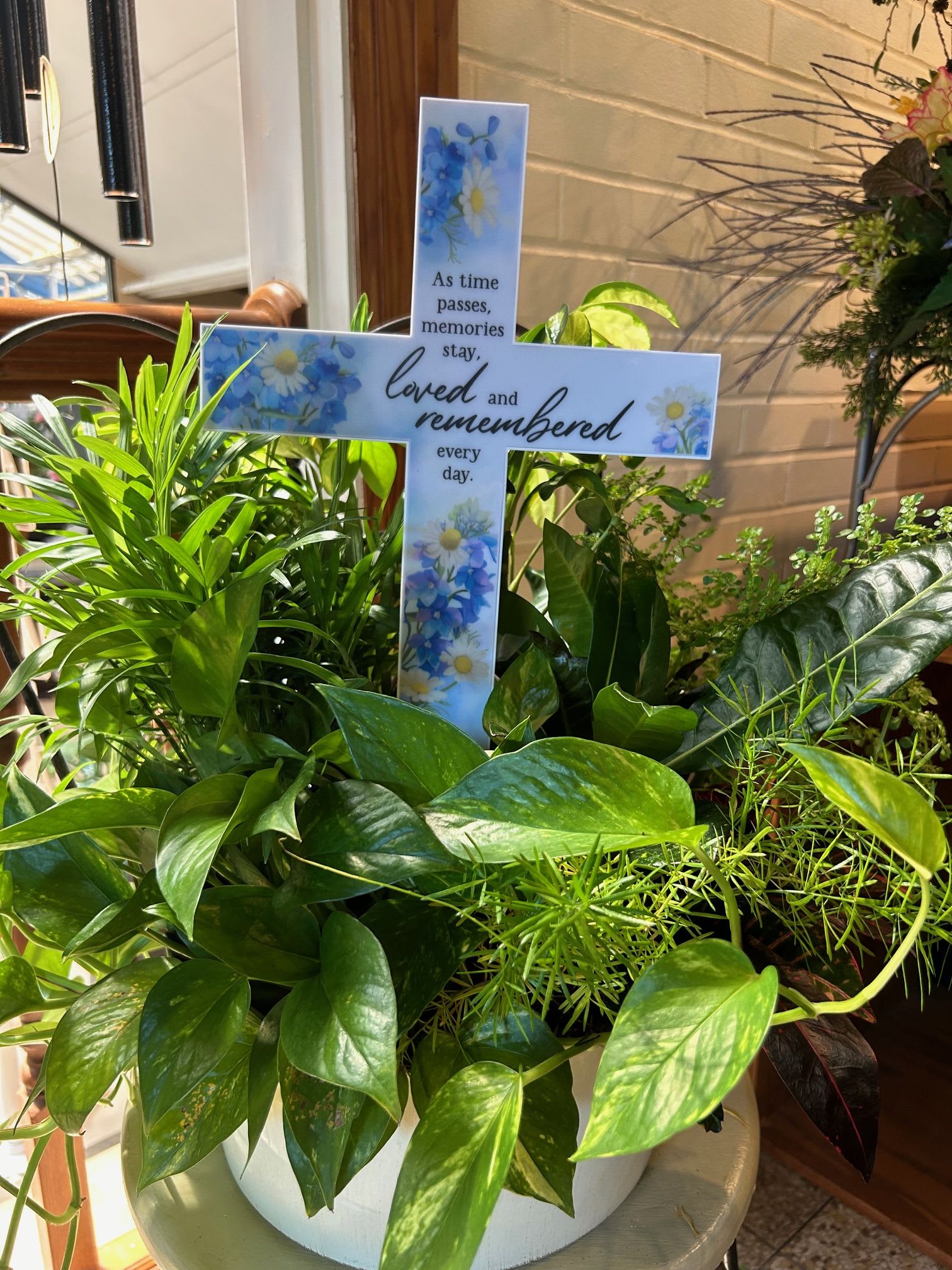 Solar Cross with Mixed Container Garden of Green Plants - A wonderful tribute to celebrate and remember your special someone.  The solar cross is weather resistant and can be placed outdoors.  The Mixed Container of Green Plants is perfect for a special place indoors or your favorite outdoor space while the weather is warm.  Each and every container is unique and planted by one of our creative and talented designers.  Containers and Crosses do vary depending on the availability at the time of your order. Floral, plant, and hard good substitutions may be made as needed depending on availability. If you have any questions about your order, please call us and we will be happy to speak with you about your selection.