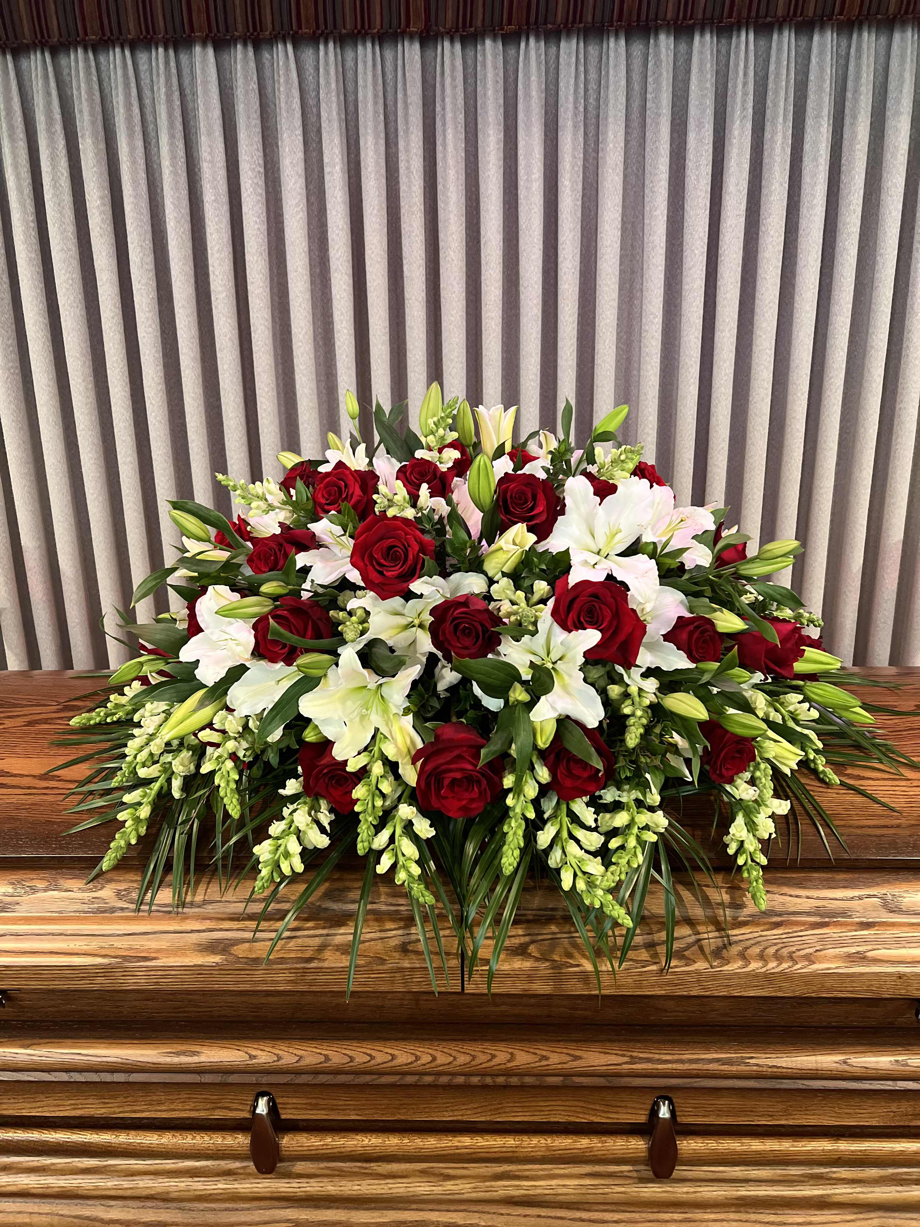Red and White Casket  - This casket arrangement includes red roses, lilies, snapdragons, and seasonal greenery.    Standard size is half casket, deluxe is 3/4 and premium is full casket.