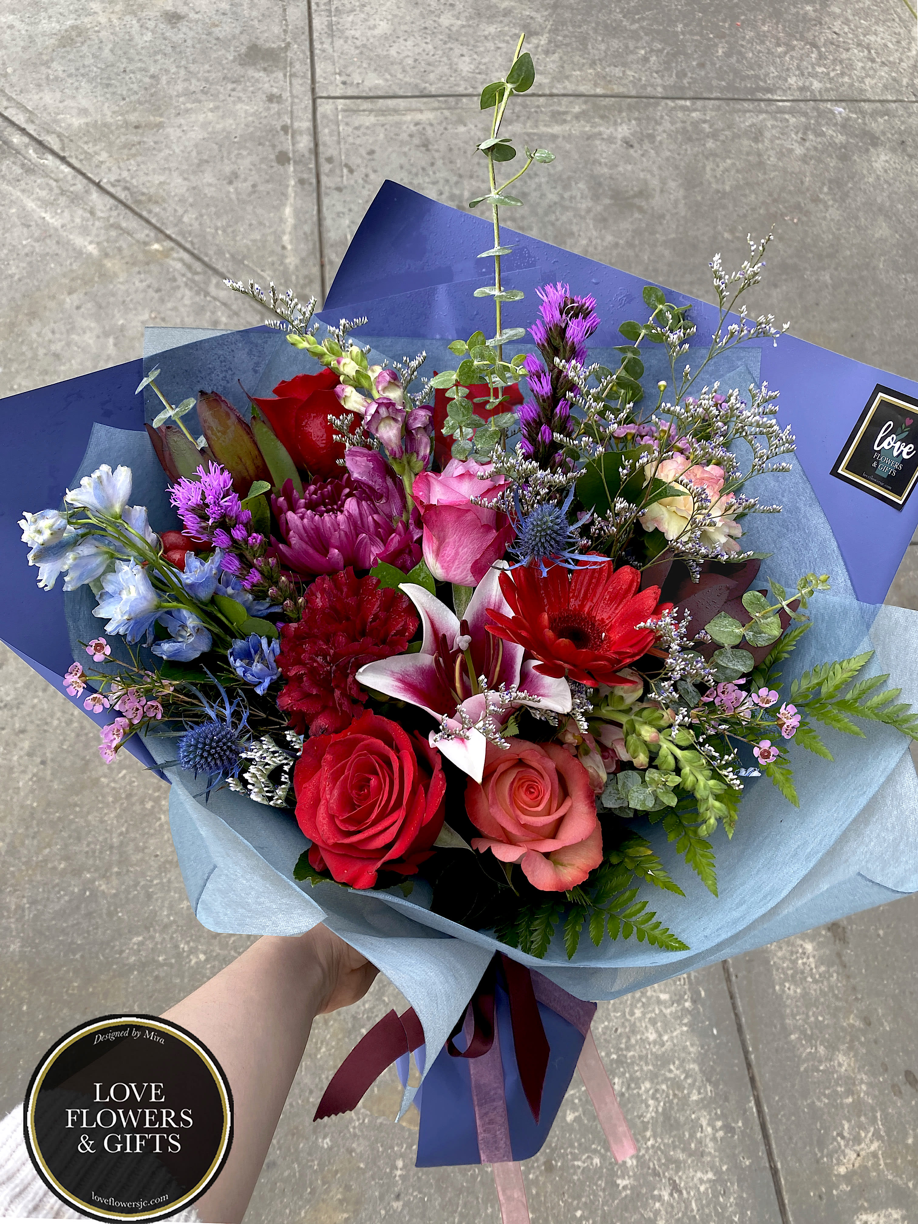 Burgundy Blues (Wrapped Bouquet) Burgundy Blues (Wrapped Bouquet) - A more elegant arrangement, perfect for the season, made in burgundy, blues, and hints of violets wrapped in high-quality imported floral mesh and paper. (Vase is not included)