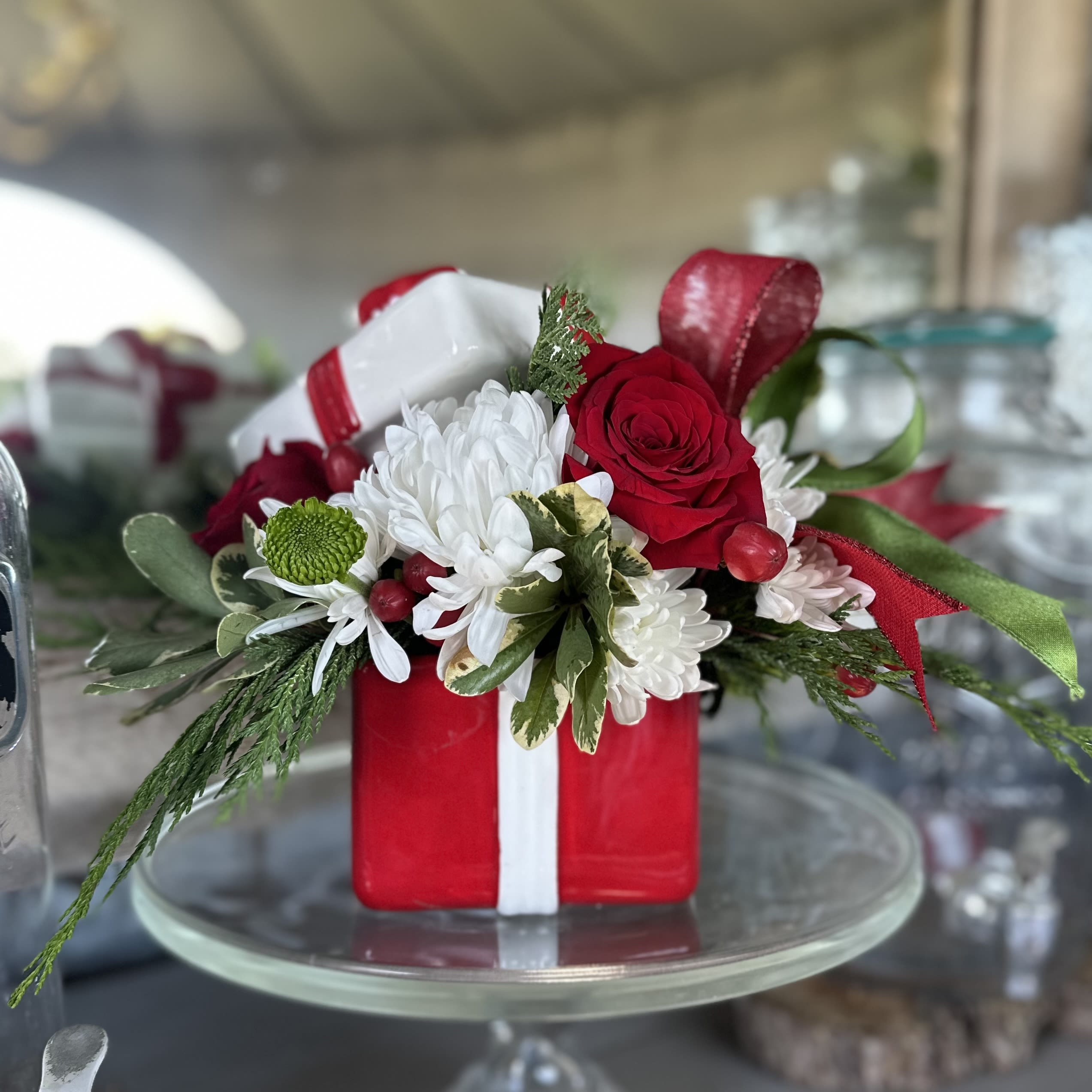 Merry &amp; Bright - Celebrate the season with our Merry &amp; Bright arrangement — a joyful burst of holiday color and cheer. Designed in a festive red gift box, this arrangement features classic red roses, crisp white blooms, fresh evergreens, and playful ribbon accents. Perfect as a table centerpiece or thoughtful holiday gift, it’s sure to spread warmth and sparkle all season long.  