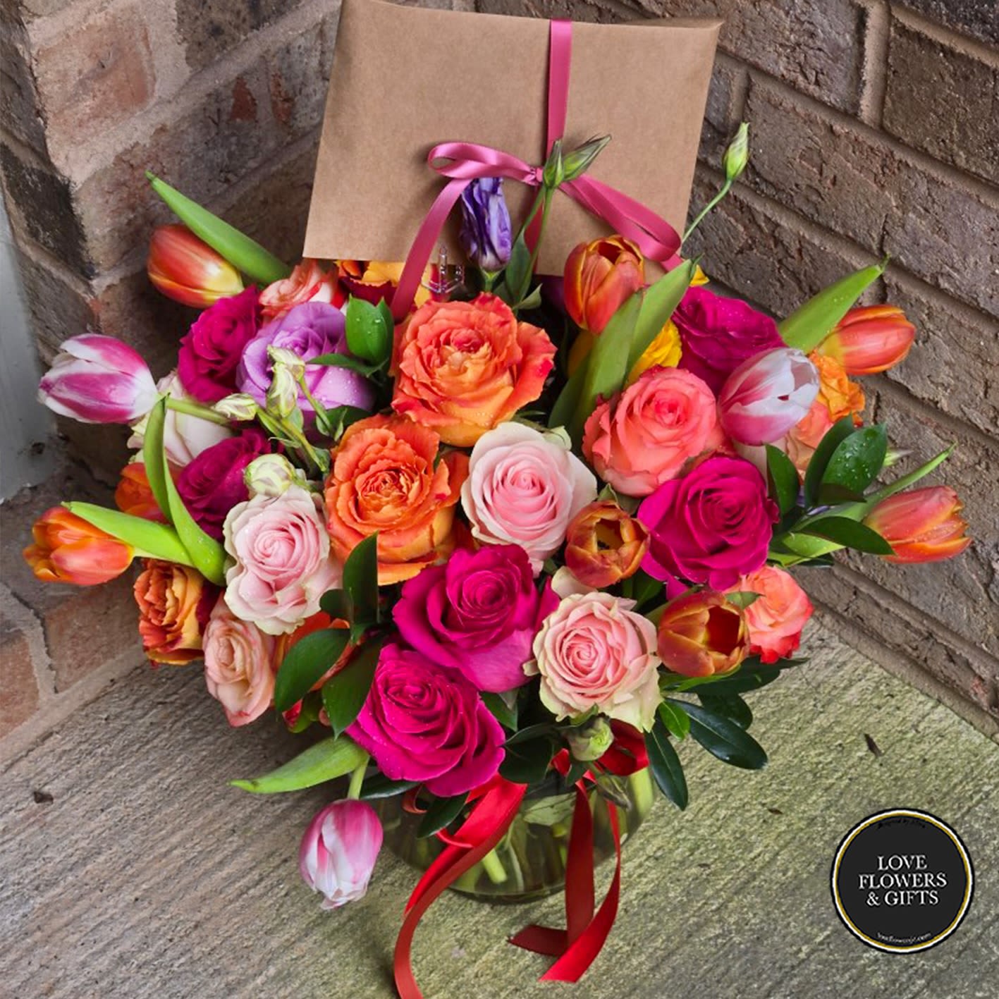 Roses &amp; Tulips  - Warm assorted roses, lilies, and tulips in a round glass vase. 