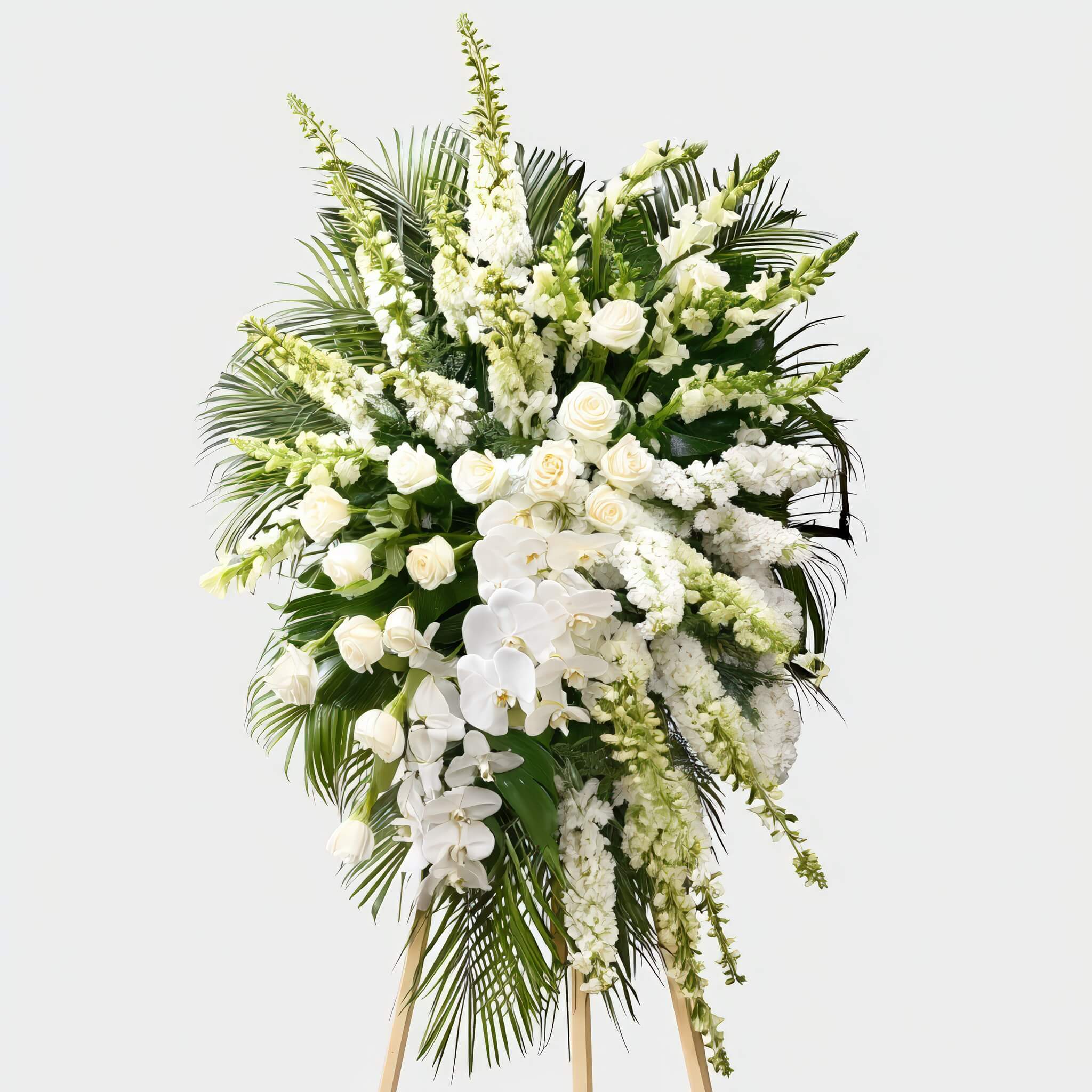 Serenity in Bloom Serenity in Bloom - A serene and graceful standing spray designed with elegant white blooms and tropical greens. Featuring cascading orchids, roses, and layered textures of snapdragons and stock—this tribute brings peace and purity to moments of remembrance.