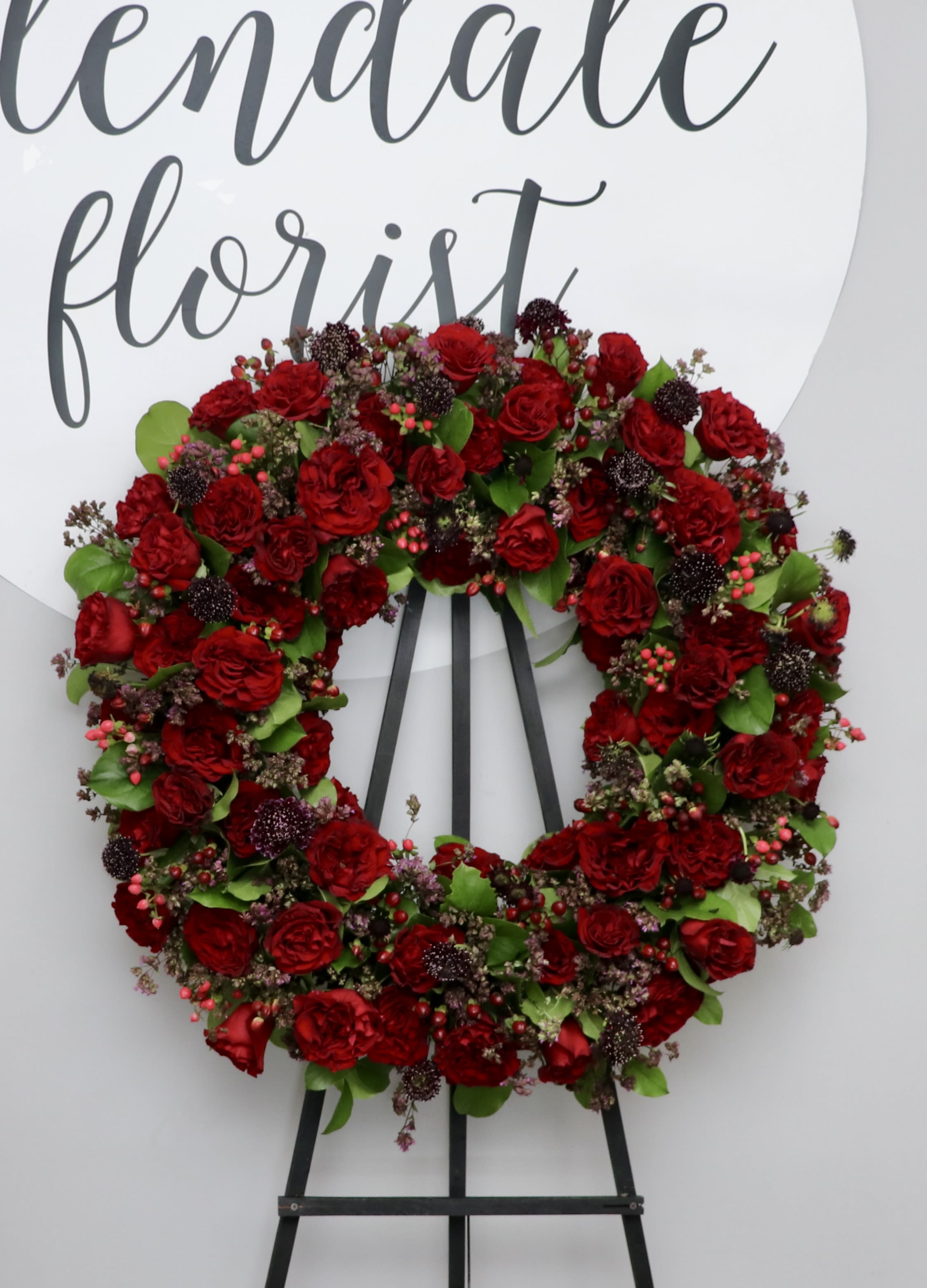 Ambar Grace - This wreath includes premium Ecuadorian red roses mixed with seasonal greenery.     We include easel, printed banner and delivery (some fees may apply). An additional banner can be added for $15    Standard size is 30'', deluxe is 36'', and premium is 42''.
