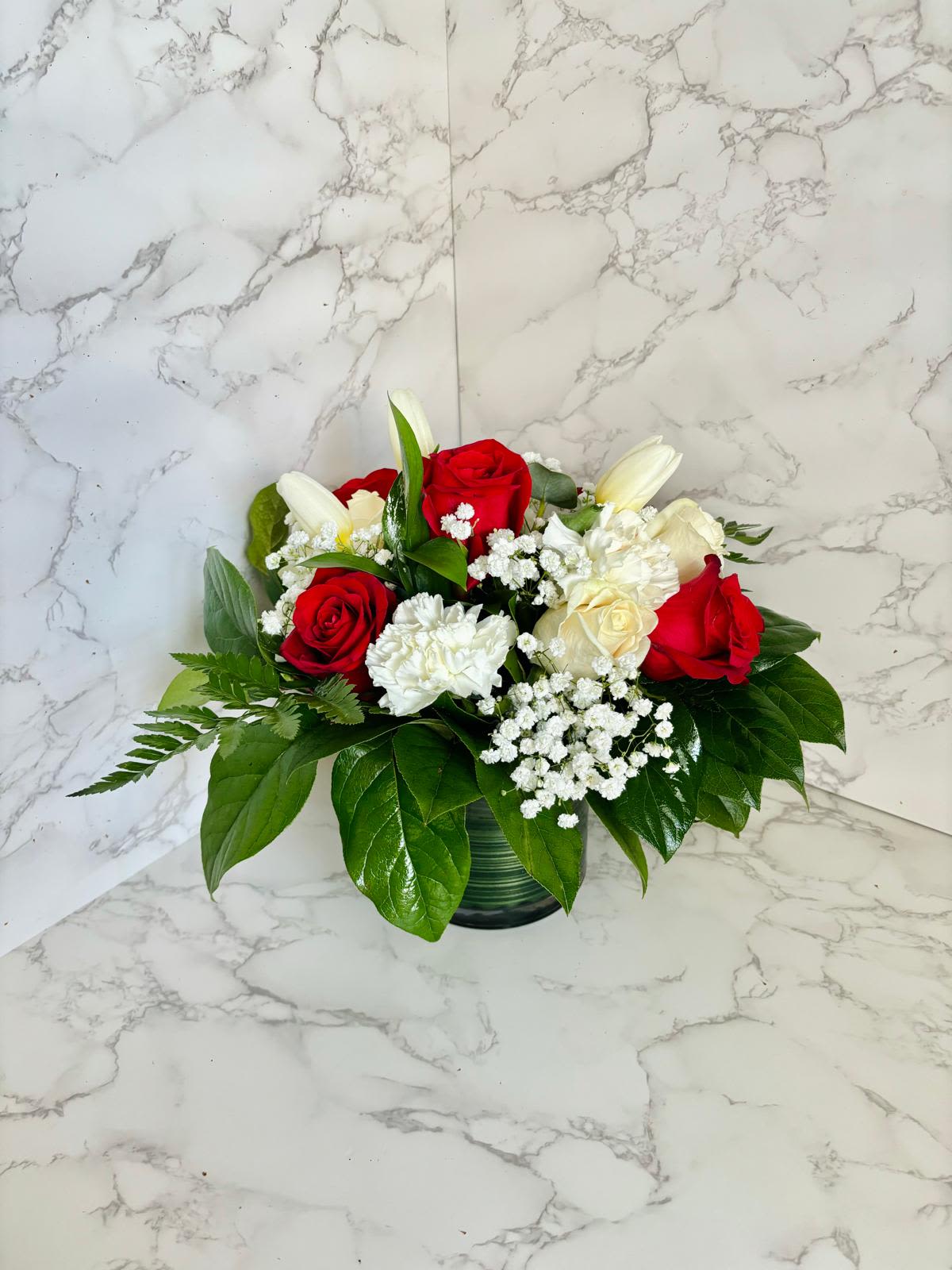 Red &amp; White Harmony Vase / Arreglo de Rosas Rojas y Blancas en Florero - Red &amp; White Harmony Vase / Arreglo de Rosas Rojas y Blancas en Florero  A timeless mix of red and white roses paired with lilies, carnations, and baby’s breath, beautifully arranged in a clear glass vase. This elegant combination symbolizes love, peace, and purity — perfect for any occasion where you want to express heartfelt emotions with grace and style.  Una combinación clásica de rosas rojas y blancas con lirios, claveles y gypsophila, elegantemente dispuestas en un florero de vidrio transparente. Este arreglo representa amor, paz y pureza — ideal para expresar sentimientos sinceros en cualquier ocasión especial.  Perfect for / Perfecto para: Anniversaries, romantic gestures, sympathy, or special celebrations. Includes / Incluye: Fresh red and white roses, lilies, carnations, baby’s breath, and greenery in a glass vase. Note / Nota: Replace water and trim stems every 1–2 days for freshness.