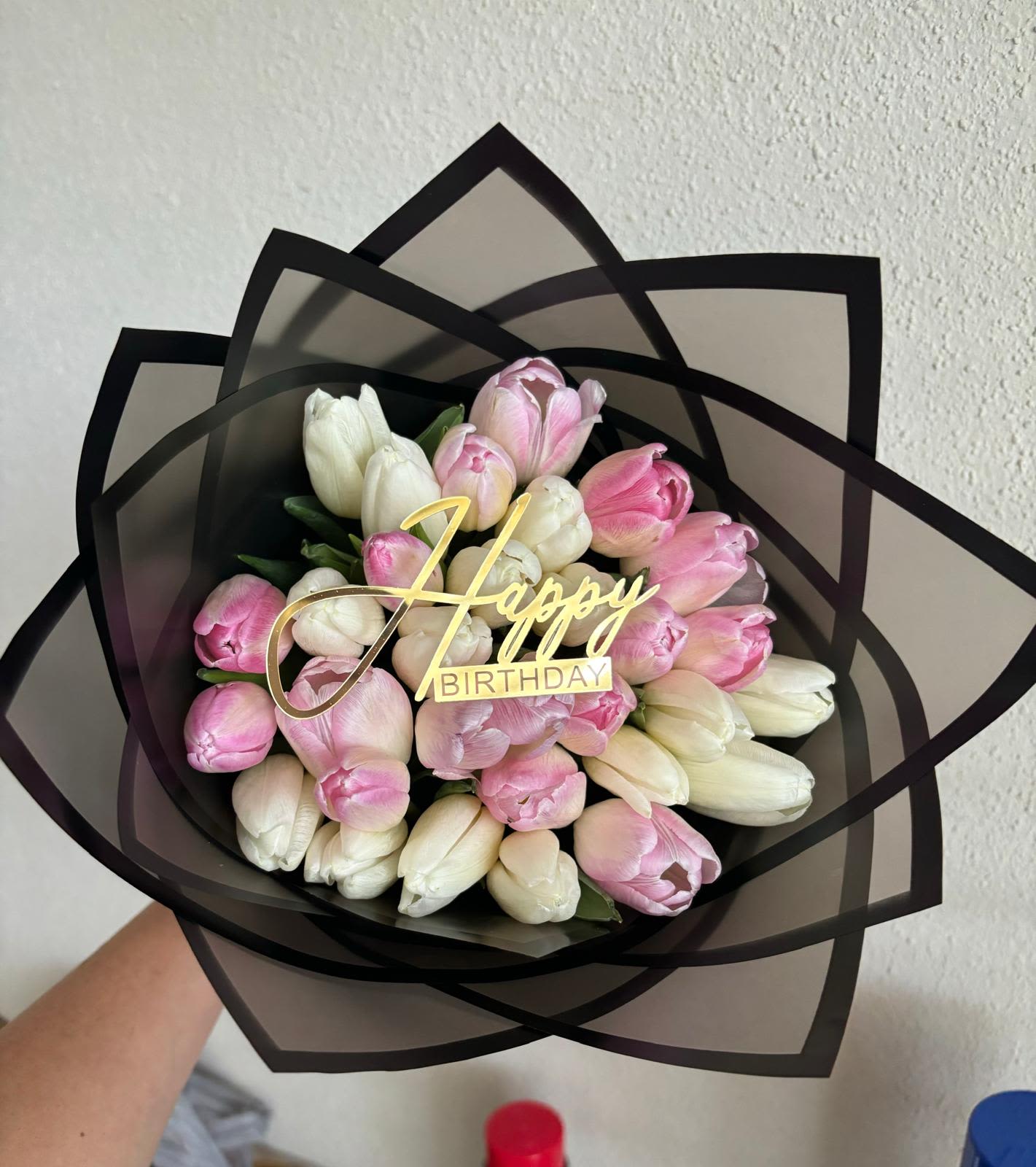 Birthday Tulip Bouquet / Ramo de Tulipanes de Cumpleaños - Birthday Tulip Bouquet / Ramo de Tulipanes de Cumpleaños  A charming birthday surprise featuring soft pink and creamy white tulips, beautifully arranged and wrapped in modern black frosted paper. Adorned with a golden “Happy Birthday” topper, this bouquet blends elegance and joy — the perfect gift to make their special day unforgettable.  Un encantador detalle de cumpleaños con tulipanes en tonos rosados y blancos cremosos, elegantemente envueltos en papel negro translúcido. Decorado con un topper dorado de “Happy Birthday”, este ramo combina elegancia y alegría — el regalo ideal para un cumpleaños inolvidable.  Perfect for / Perfecto para: Birthdays, celebrations, or thoughtful surprises. Includes / Incluye: Fresh tulips (pink &amp; white), modern wrapping, and gold topper. Note / Nota: Subject to availability. Tulips may take time to open once in water.