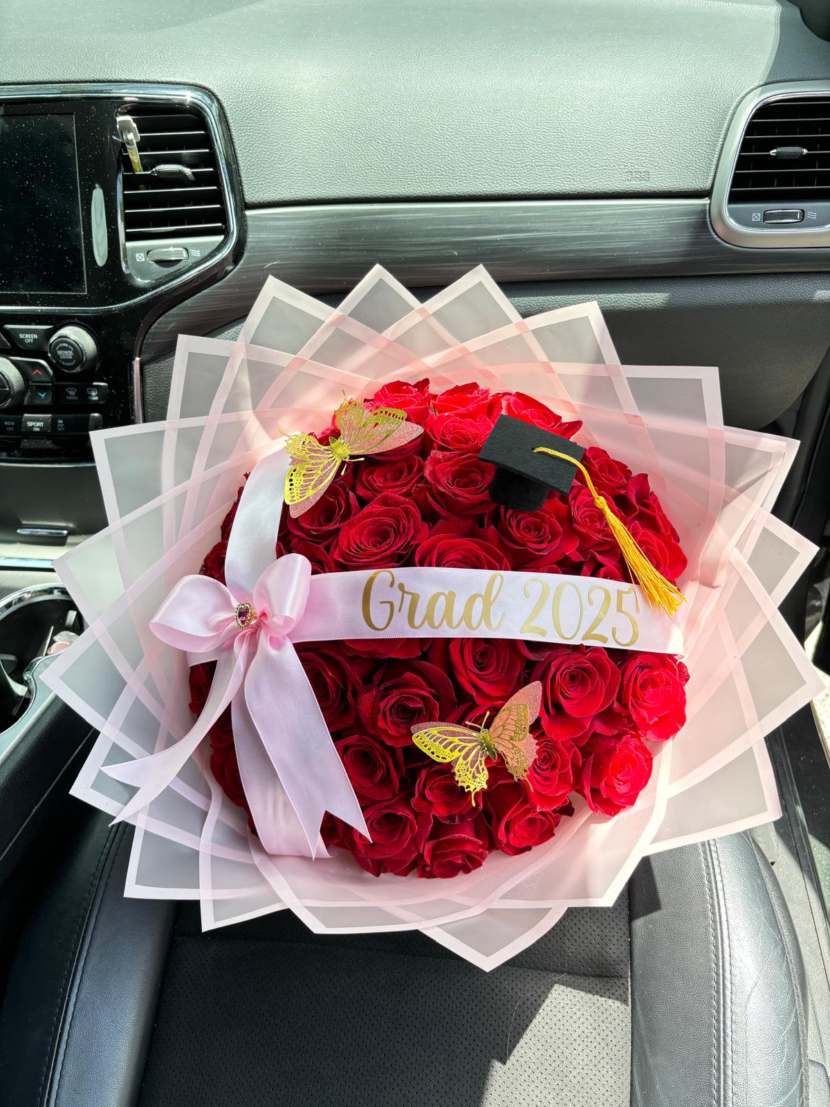 Graduation Bouquet 2025 (Pink Edition) / Ramo de Graduación 2025 (Edición Rosada) - Graduation Bouquet 2025 (Pink Edition) / Ramo de Graduación 2025 (Edición Rosada)  A luxurious bouquet designed to celebrate one of life’s proudest moments. Our Graduation Bouquet 2025 (Pink Edition) features radiant red roses, delicate gold butterflies, and a mini graduation cap, beautifully wrapped in soft pink layers with a custom “Grad 2025” ribbon. A perfect mix of elegance and celebration to honor a special graduate.  Un lujoso ramo creado para celebrar uno de los logros más importantes. Nuestro Ramo de Graduación 2025 (Edición Rosada) combina rosas rojas vibrantes, mariposas doradas y un pequeño birrete, envuelto en delicadas capas rosadas con cinta personalizada “Grad 2025”. Una mezcla perfecta de elegancia y alegría para homenajear al graduado o graduada.  Perfect for / Perfecto para: Graduation gifts and milestone celebrations. Includes / Incluye: Fresh red roses, pink wrap, butterflies, ribbon, and mini cap. Note / Nota: Custom text available upon request.