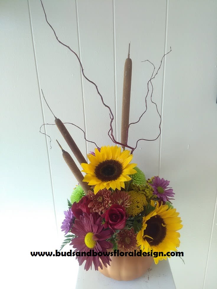 ML's Sunny Pumpkin ML's Sunny Pumpkin - In a reusable ceramic pumpkin, this festive mix of blooms will surely impress!!   Seasonal colors and flowers such as*: sunflowers, yarro, red rover daisies, solidago, mums, buttons, miniature roses, curly willow, and cat tails.   24"H x 10"W  *Exact colors of each flower may not always be available, however, the look and feel will stay the same.