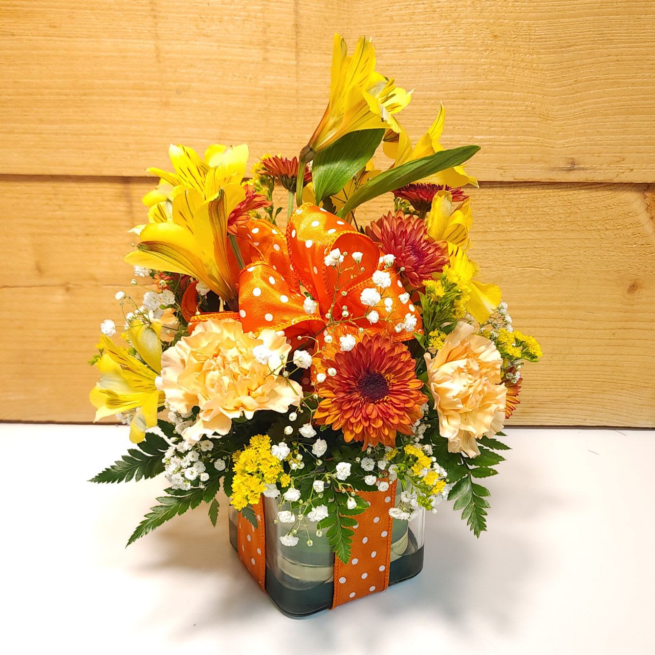 Polka Dot Blooms Bouquet - Orange Polka Dot Blooms Bouquet - Orange - Polka Dot Blooms Bouquet - Orange,  featuring a 4" glass cubed container filled with beauty and all accented with a fun orange and white polka dot ribbon and bow.    PLEASE NOTE: Some flowers, vases and other products pictured are subject to availability, and may be substituted for a similar item if unavailable according to our substitution policy.
