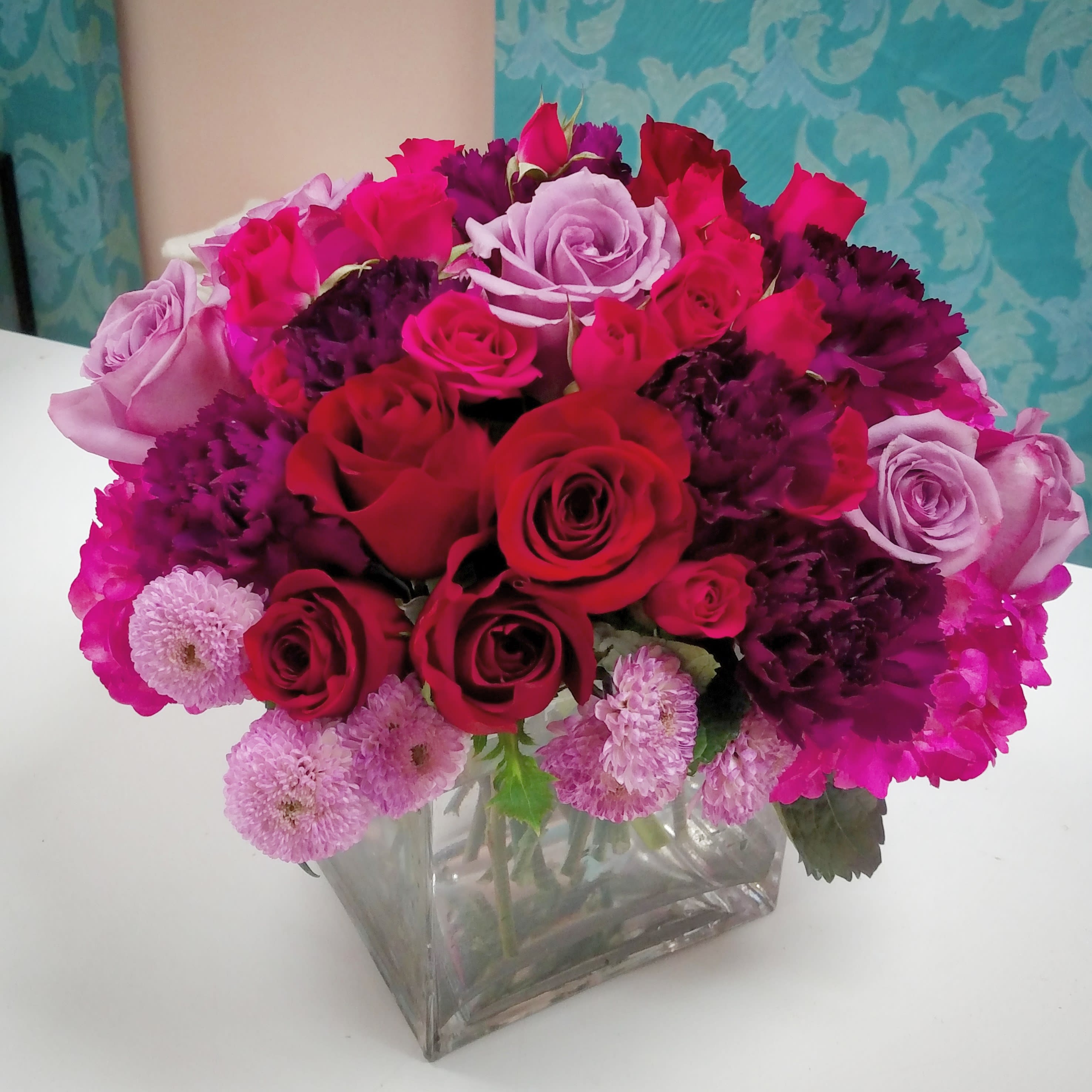 Radiant Beauty Bouquet - Radiant deep reds plum and hot pink elegantly designed with lavender give this arrangement a stunning &quot;WOW&quot; head turn by all who see it. Hydrangea, 18 rose stems of mixed colors, mums and carns create this perfect mix. 