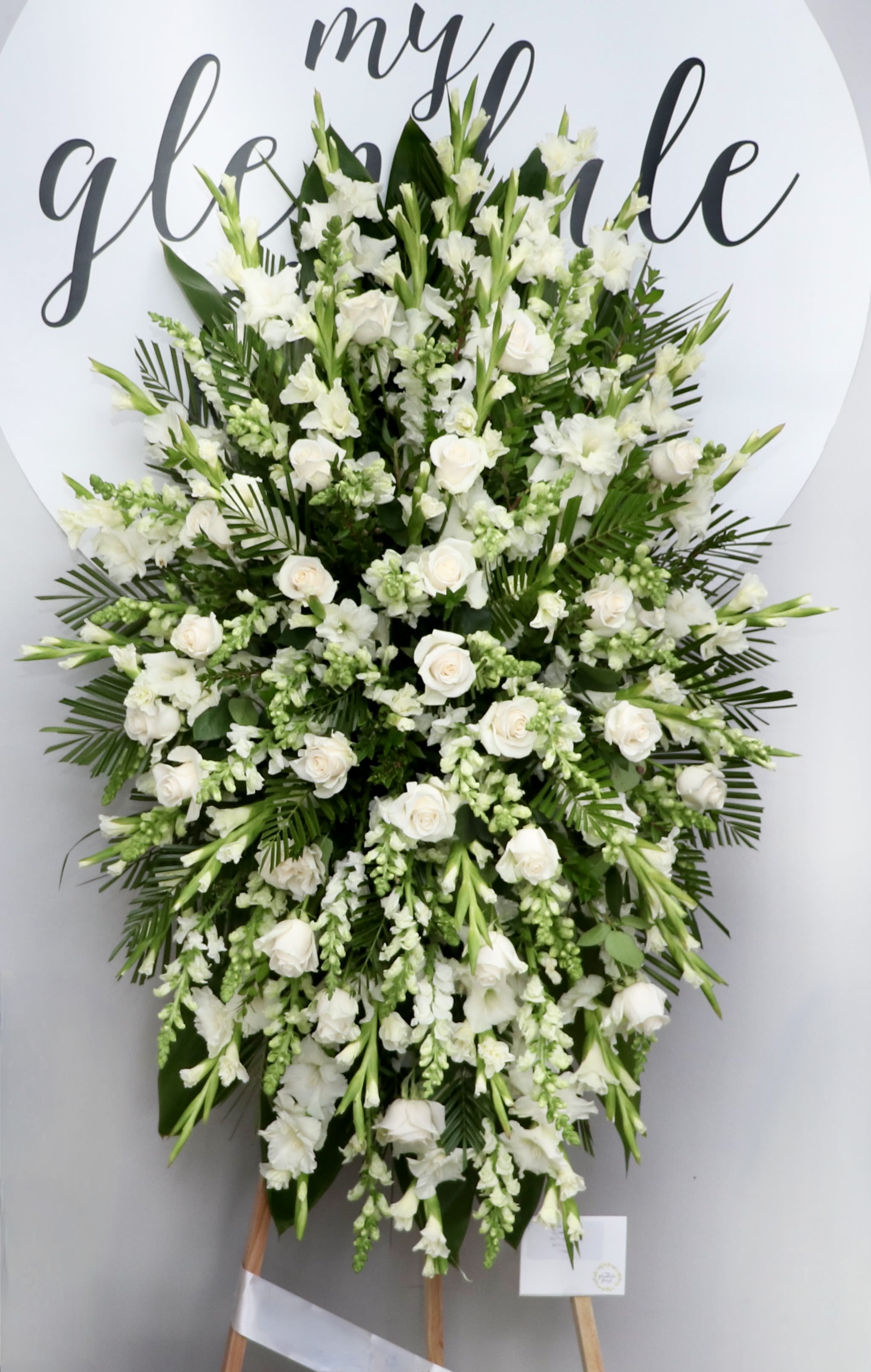 All White Spray  - This all white spray is composed of white roses, white gladiolus, and snap dragons.   We include easel, printed banner, and delivery (some fees may apply). An additional banner can be added for $15.  Standard size is 30'' wide, deluxe is 36'', and premium is 42''.