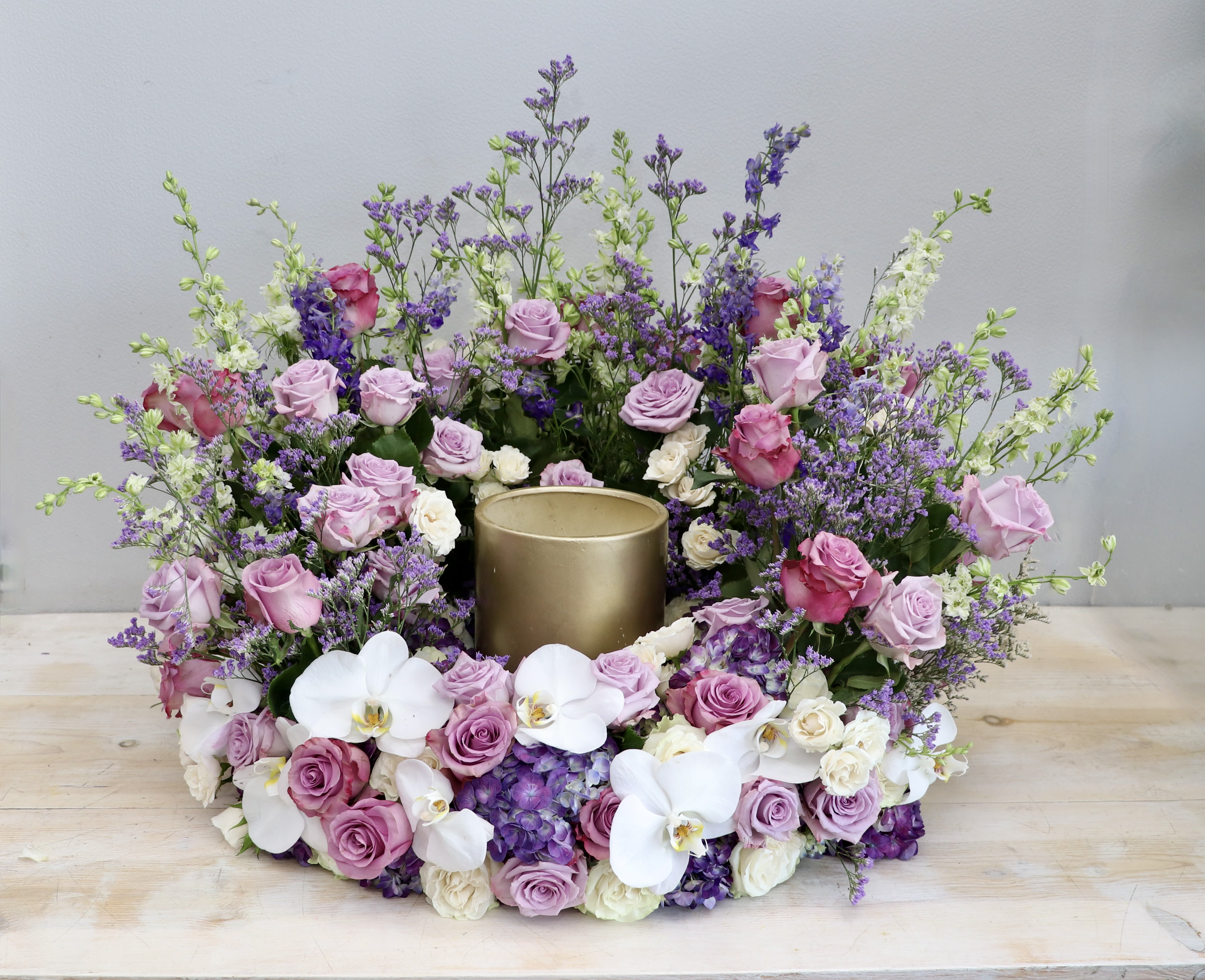 Lavender Urn Wreath - This urn wreath is made with a variety of purple and lavender flowers including roses and hydrangea. The purples are accented with beautiful white orchids. This is a lovely choice to honor your loved one.   Standard size is 30'', deluxe is 36'' and premium is 42''. Interior diameter is about 10'' for standard size.