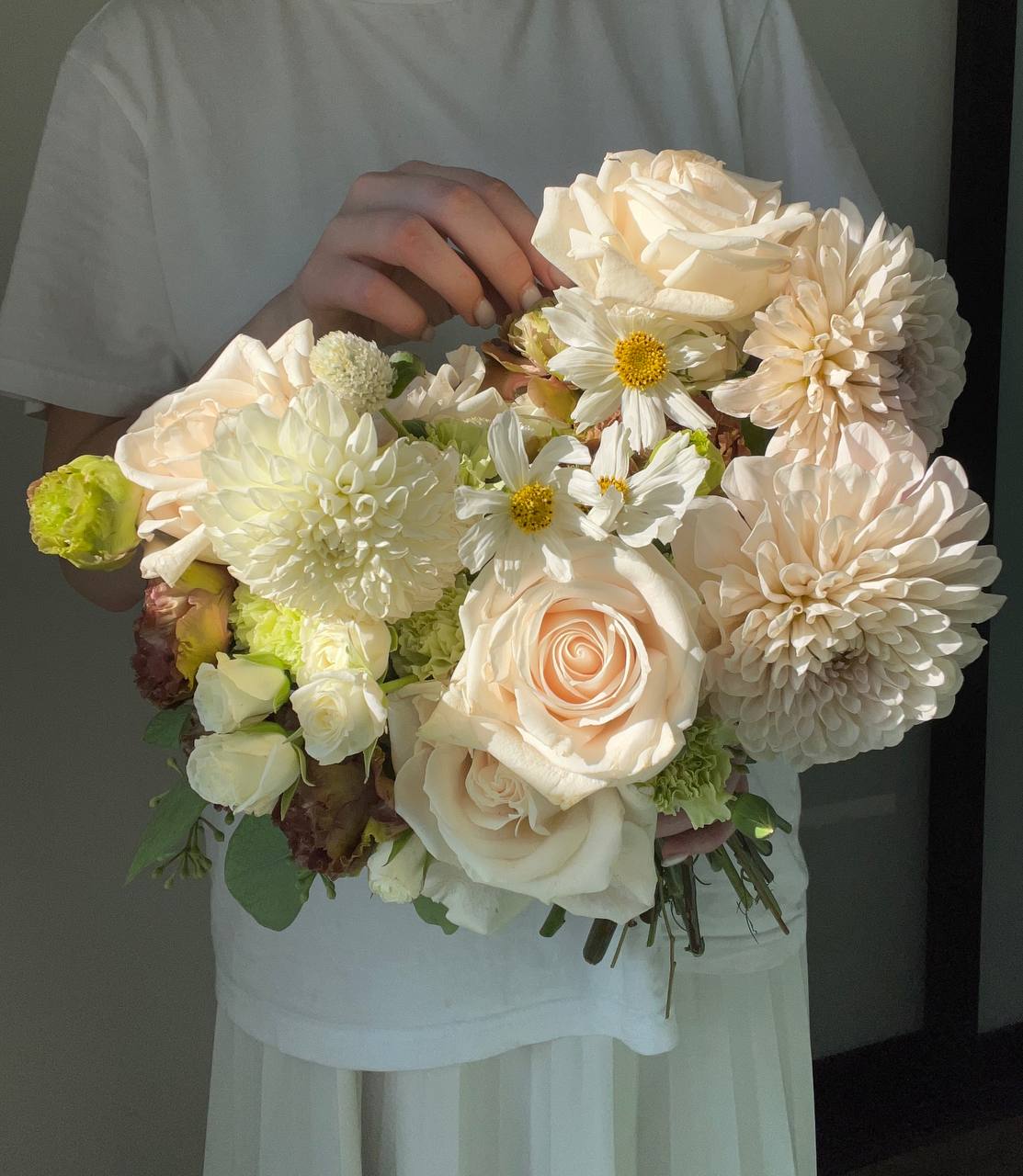 Garden Dream Garden Dream - Elegant Wedding Bouquet in Cream Tones This exquisite wedding bouquet blends soft romance with refined harmony. Featuring creamy dahlias and roses, it is beautifully complemented by delicate green dianthus and airy white spray roses. Silvery eucalyptus adds elegance, while warm brown lisianthus brings depth and charm. Perfect for a romantic, elegant, or modern classic wedding, this bouquet highlights the bride’s beauty and creates an unforgettable celebration atmosphere.