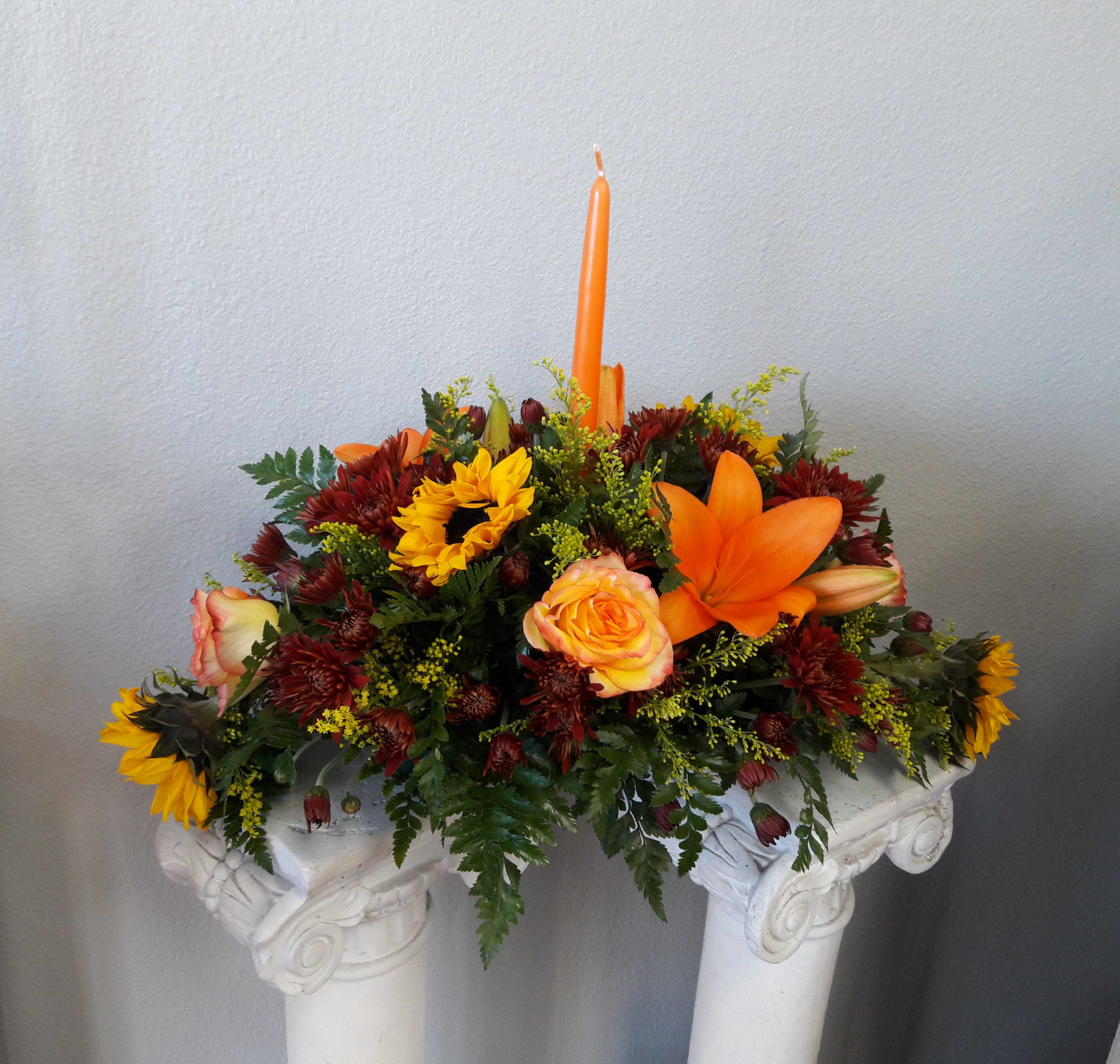 Garden of Fall - Graciously gather your family around the warm glow and classic autumn colors of this stunning Thanksgiving centerpiece. A lush variety of fall blooms are gathered under a  tall, graceful candle - perfect for decorating your Thanksgiving dinner table.