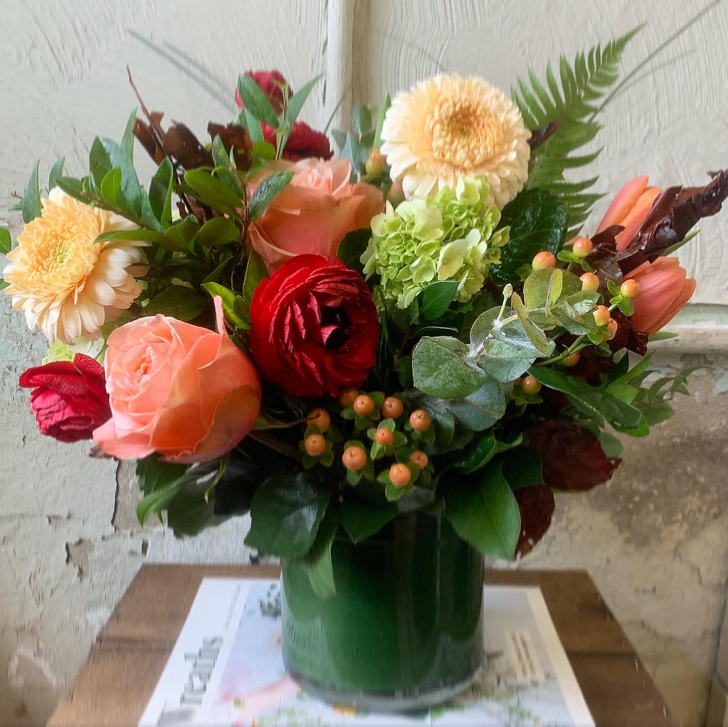 Cream of the Crop - Cream gerberas, red ranunculus, tulips and orange roses shine bright in this seasonal stunner!